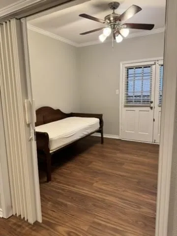 Wood-finish flooring with crown molding, ceiling fan, and exterior access