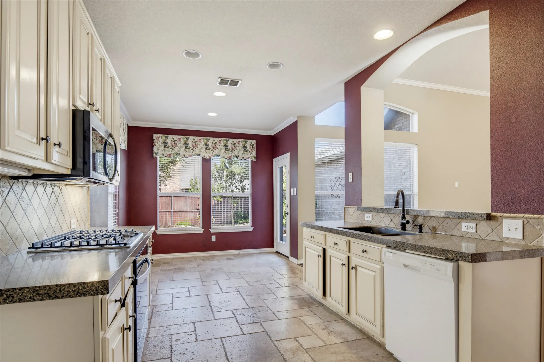 Kitchen featuring recessed lighting, a gas cooktop, tile flooring, an arched doorway, and built-in white cabinetry