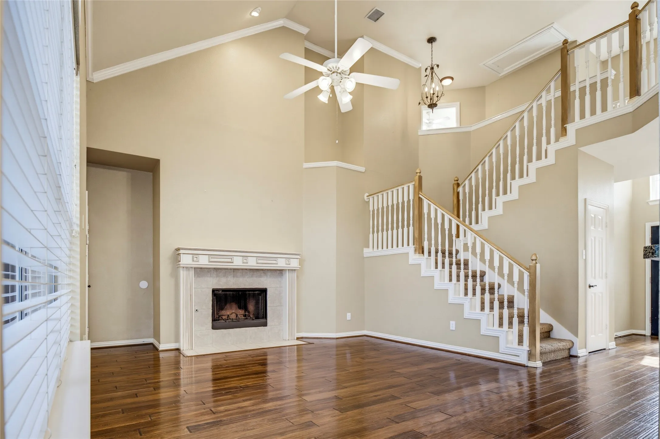 Two-story living area with wood-finish flooring, a decorative fireplace, and a multi-level staircase with wood railings