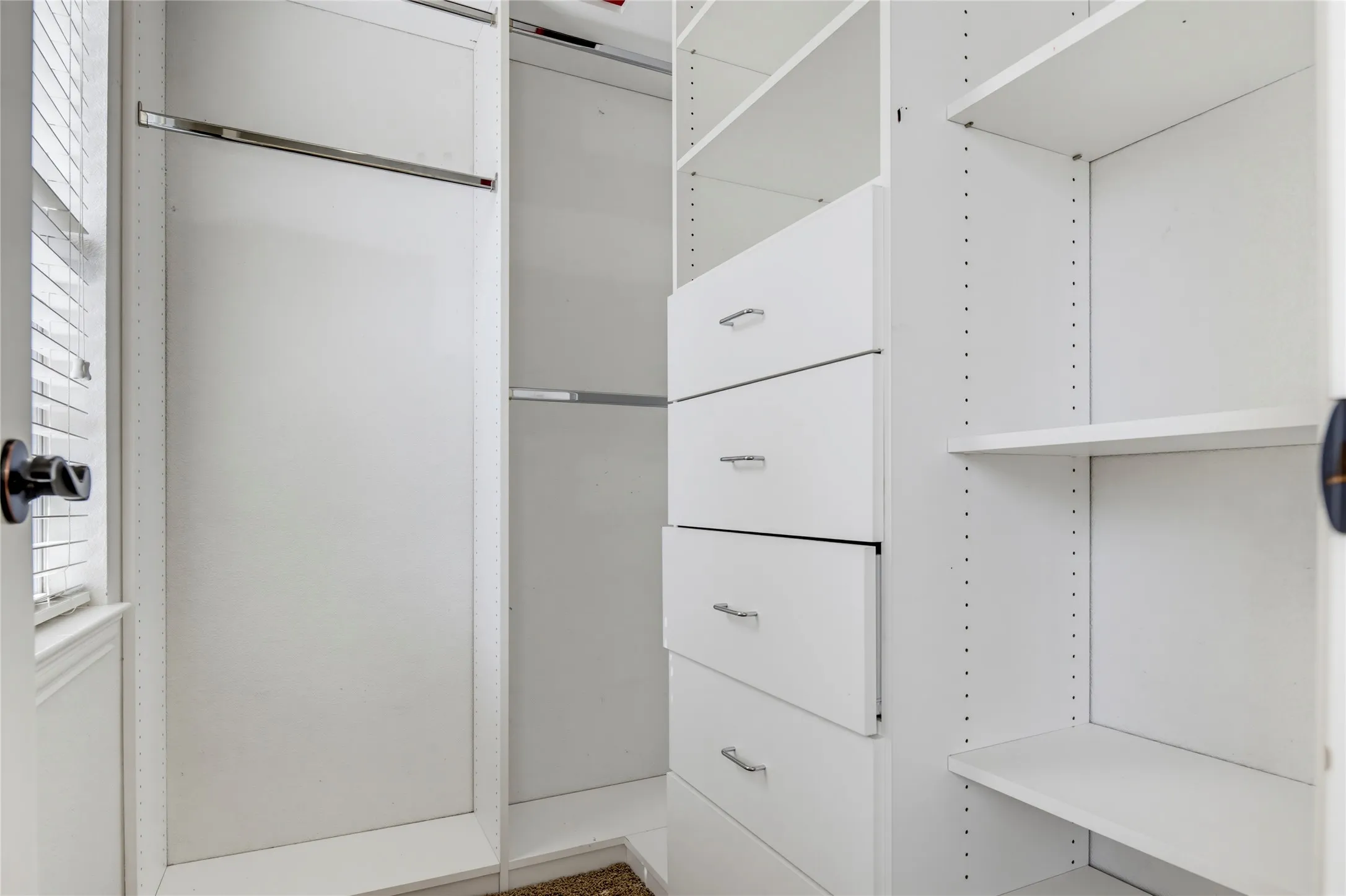 Built-in closet system featuring multiple hanging rods, adjustable shelving, and integrated drawers with chrome hardware