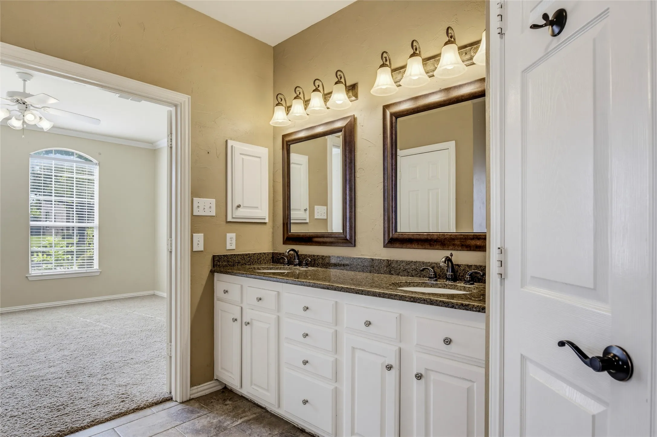 Dual vanity with dark stone countertop, undermount sinks, and framed mirrors