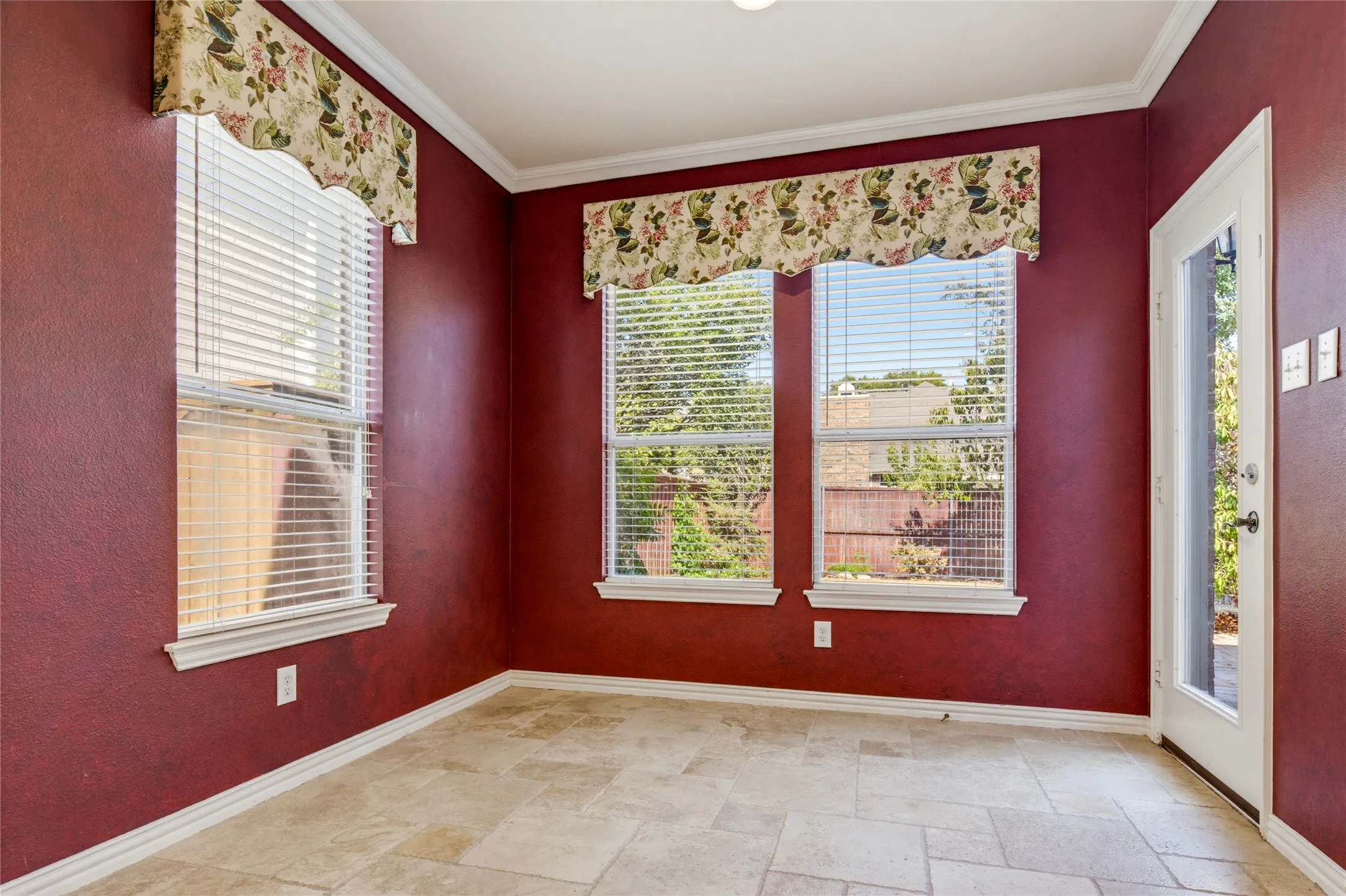 Tile flooring, multiple windows, white trim, white crown molding, and a white exterior door with window