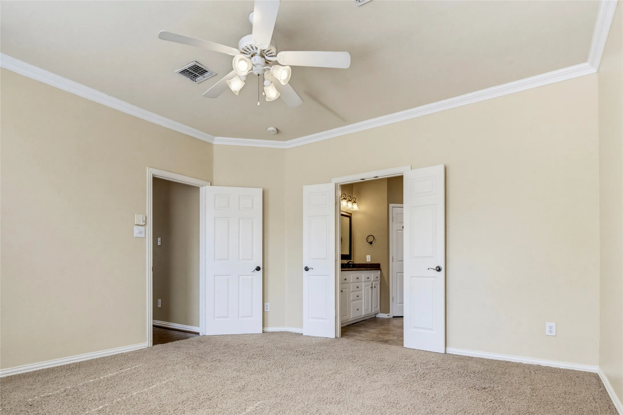 Vaulted ceiling with a ceiling fan, crown molding, neutral wall tones, and plush carpet flooring