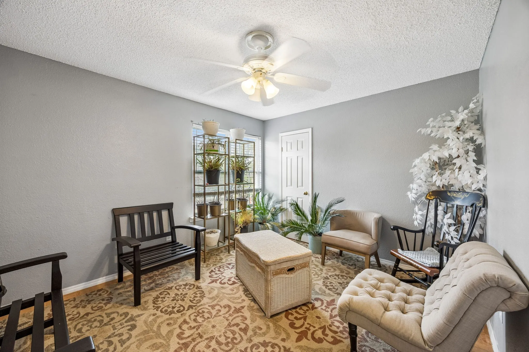 Room featuring a textured ceiling, a ceiling fan with integrated lighting, and a window providing natural illumination