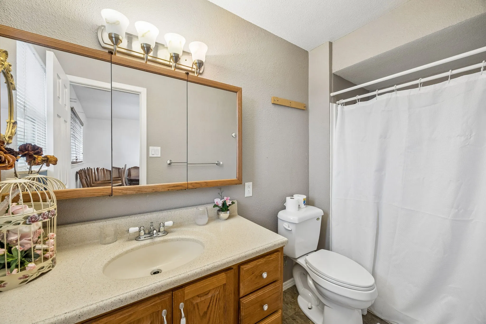 Light wood-finish vanity with an integrated sink, tri-panel mirrored medicine cabinet, and a five-light fixture
