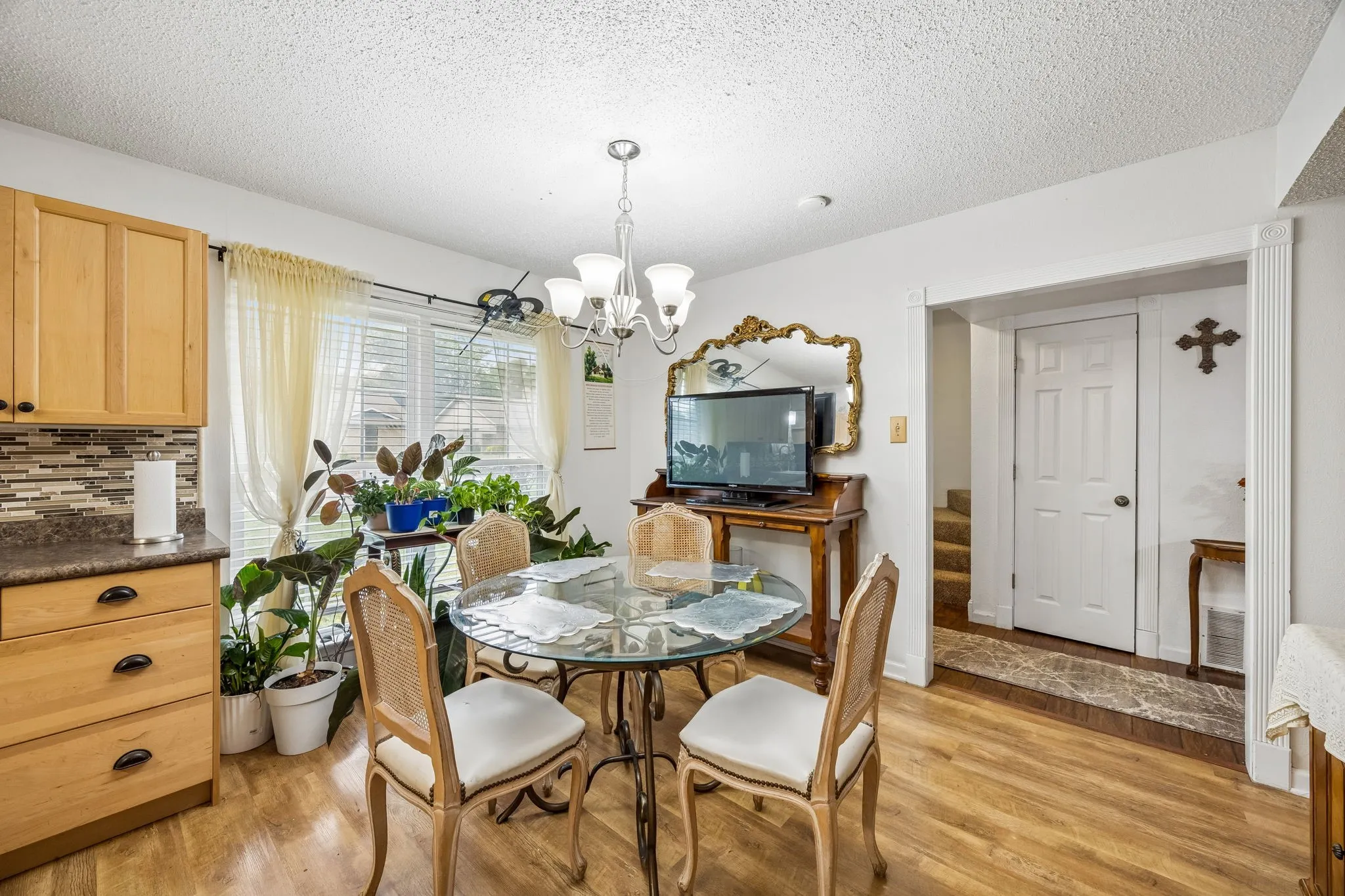 Wood-finish flooring throughout, light wood cabinetry, multi-tone tiled backsplash, and recessed lighting
