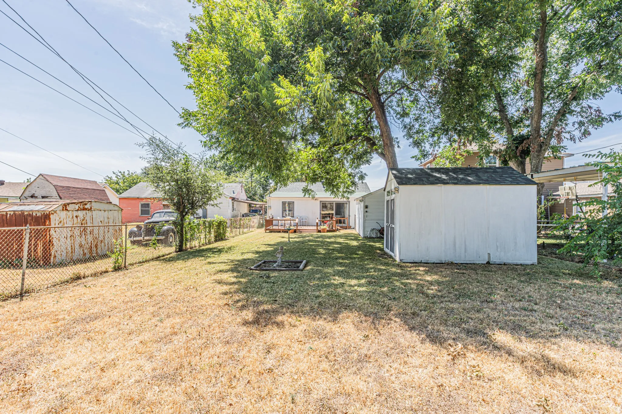 Expansive outdoor area with a white wooden shed and mature trees