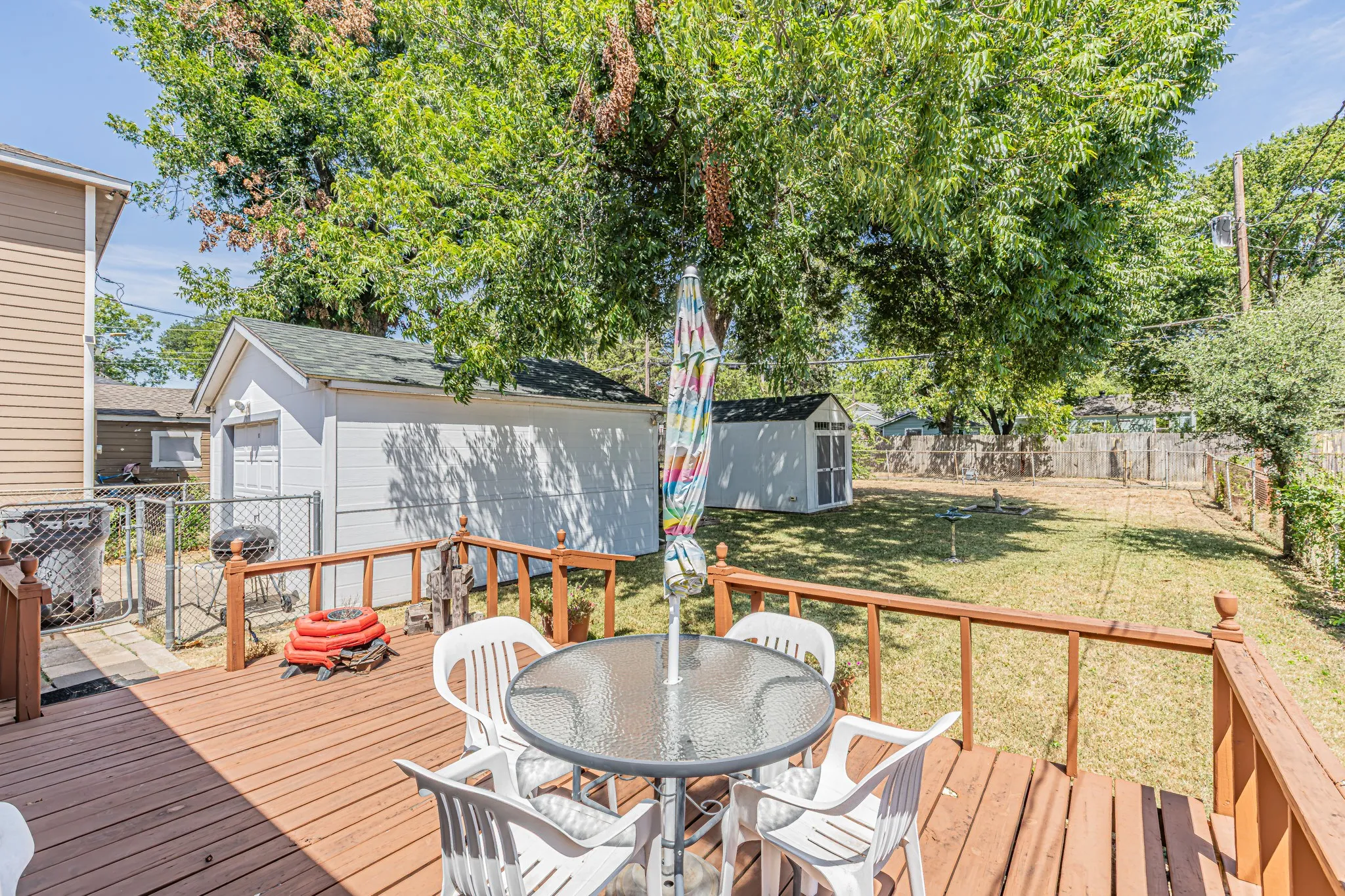 Expansive wood deck with wood railings, featuring a detached garage and a separate storage shed