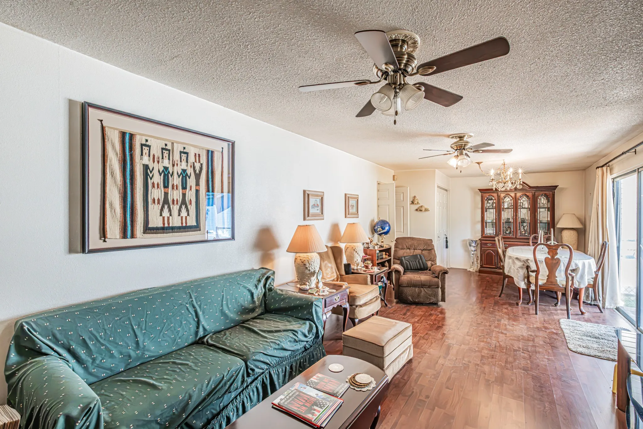 Living and dining areas featuring wood-finish flooring, multiple ceiling fans, and sliding glass doors