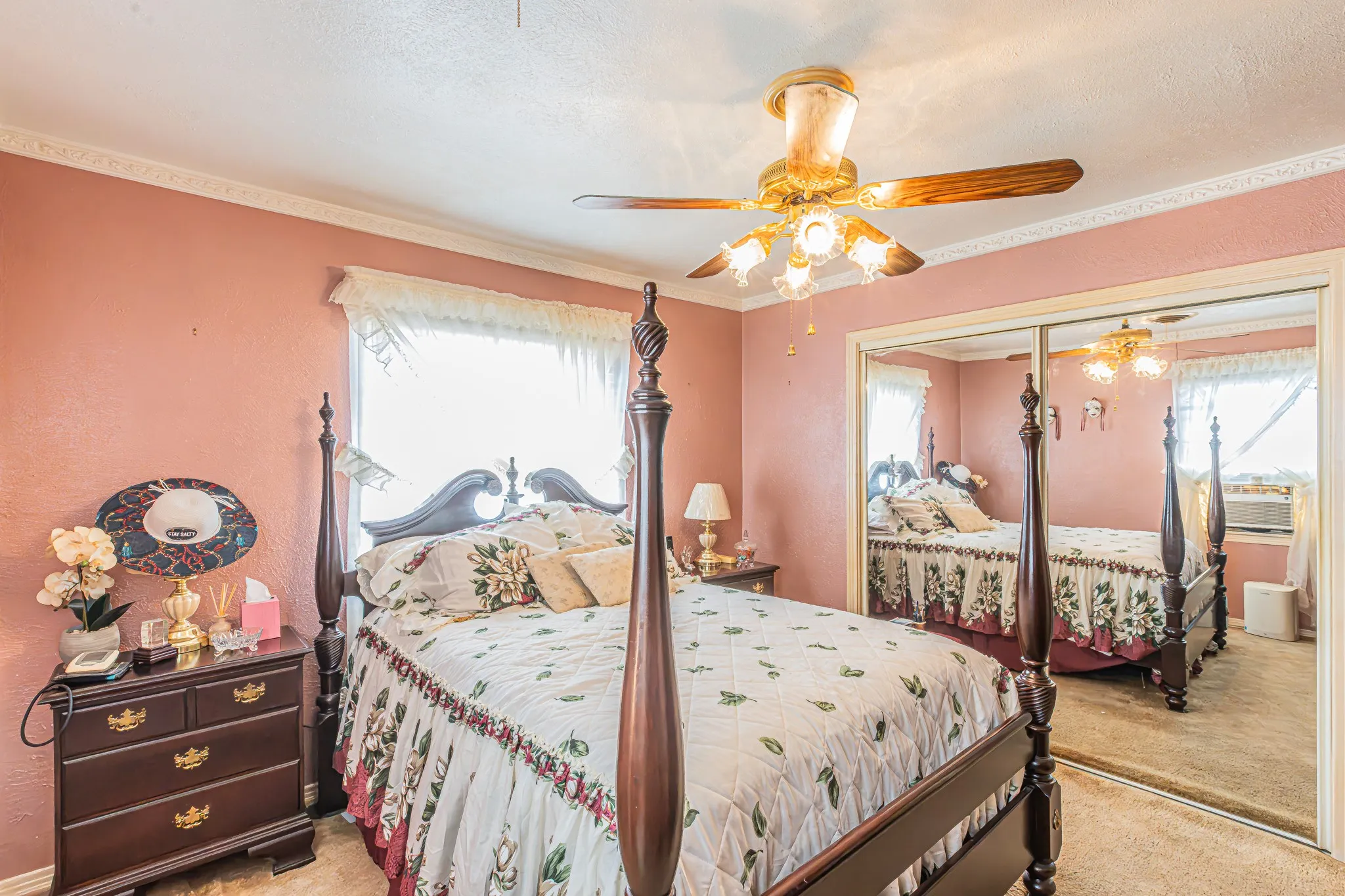 Ceiling fan with integrated lighting, mirrored closet doors, crown molding, and textile window coverings