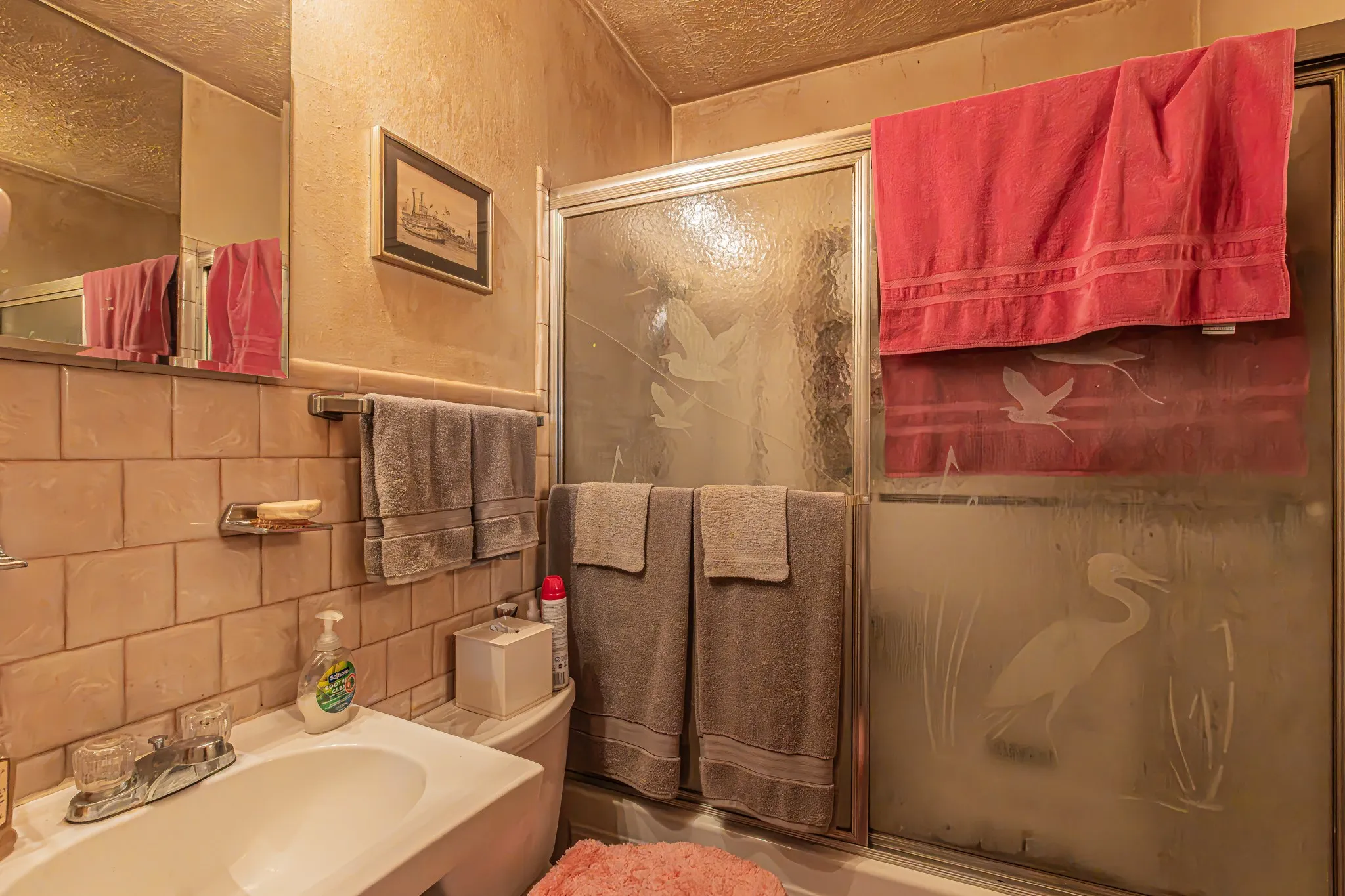 Bathroom featuring a vanity with an integrated sink, polished chrome faucet, a wall-mounted mirror, and tiled walls