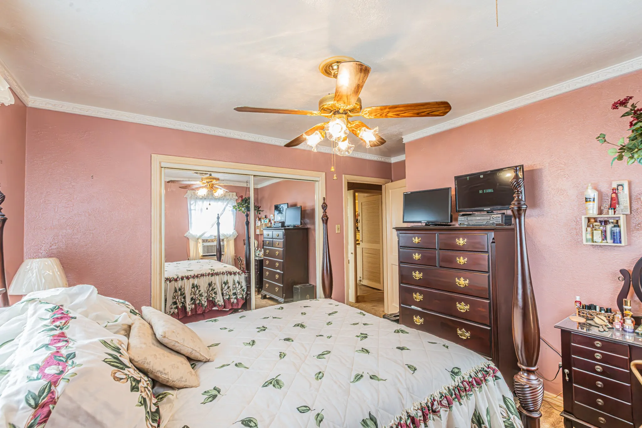 Ceiling fan with light fixture, mirrored closet doors, and crown molding