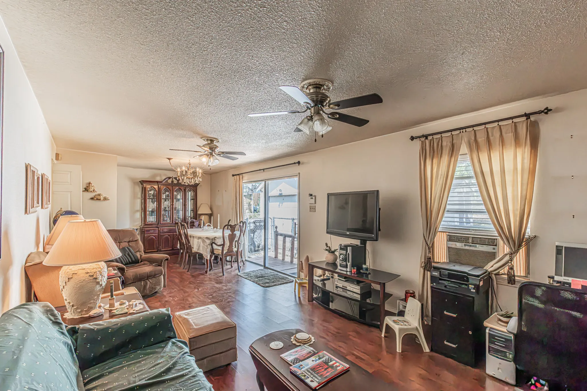 Wood-finish flooring throughout, ceiling fan with integrated lighting, chandelier lighting fixture, and sliding glass door