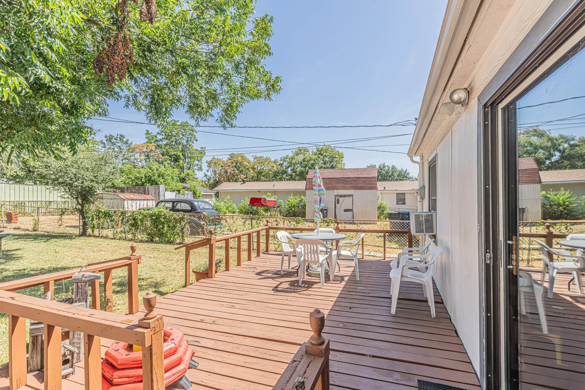 Expansive wooden deck with railing, sliding glass door access, and a manicured lawn beyond