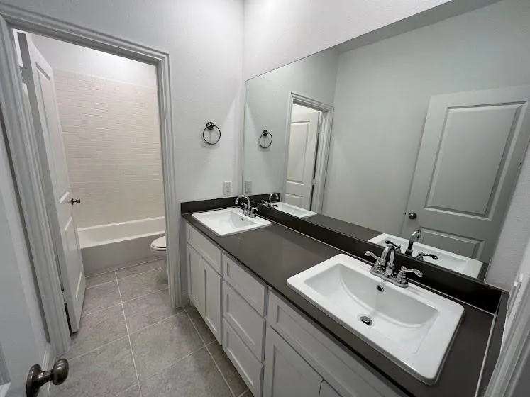 Double vanity with integrated sinks, dark countertop, and chrome fixtures