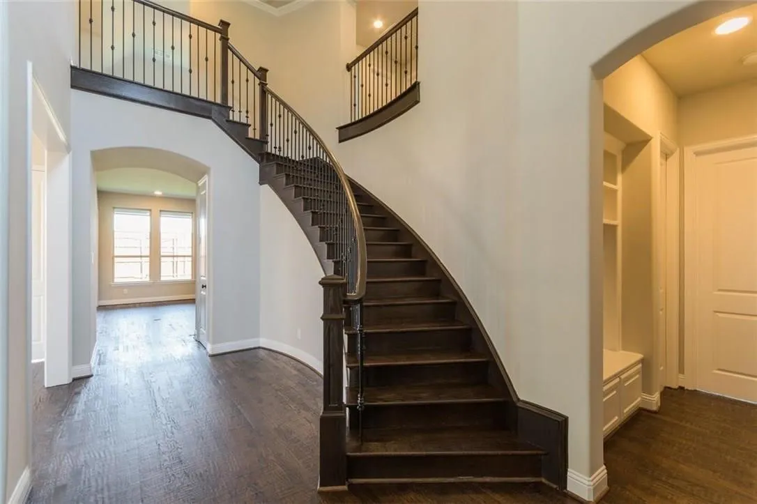 Stairs with a towering ceiling, ornamental molding, and dark wood flooring