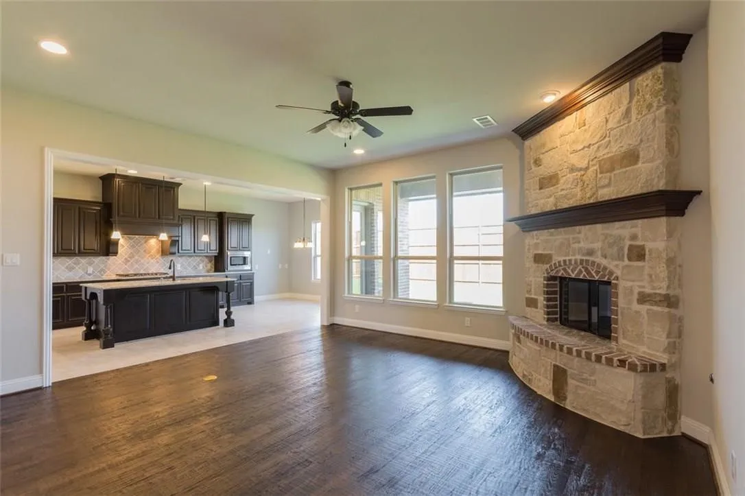 Living room featuring ceiling fan, a fireplace, nailed down hard wood flooring