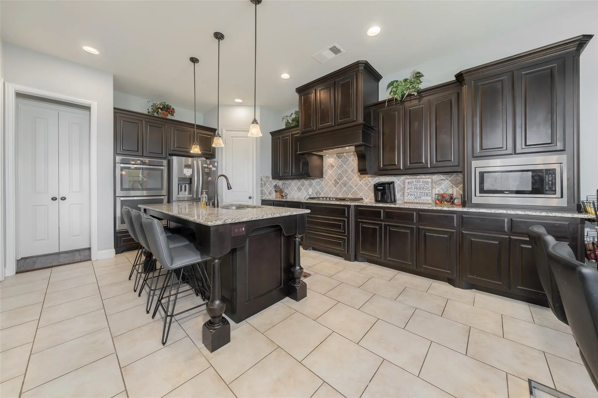 Kitchen with tasteful backsplash, stainless steel appliances, hanging light fixtures, sink, and granite countertops