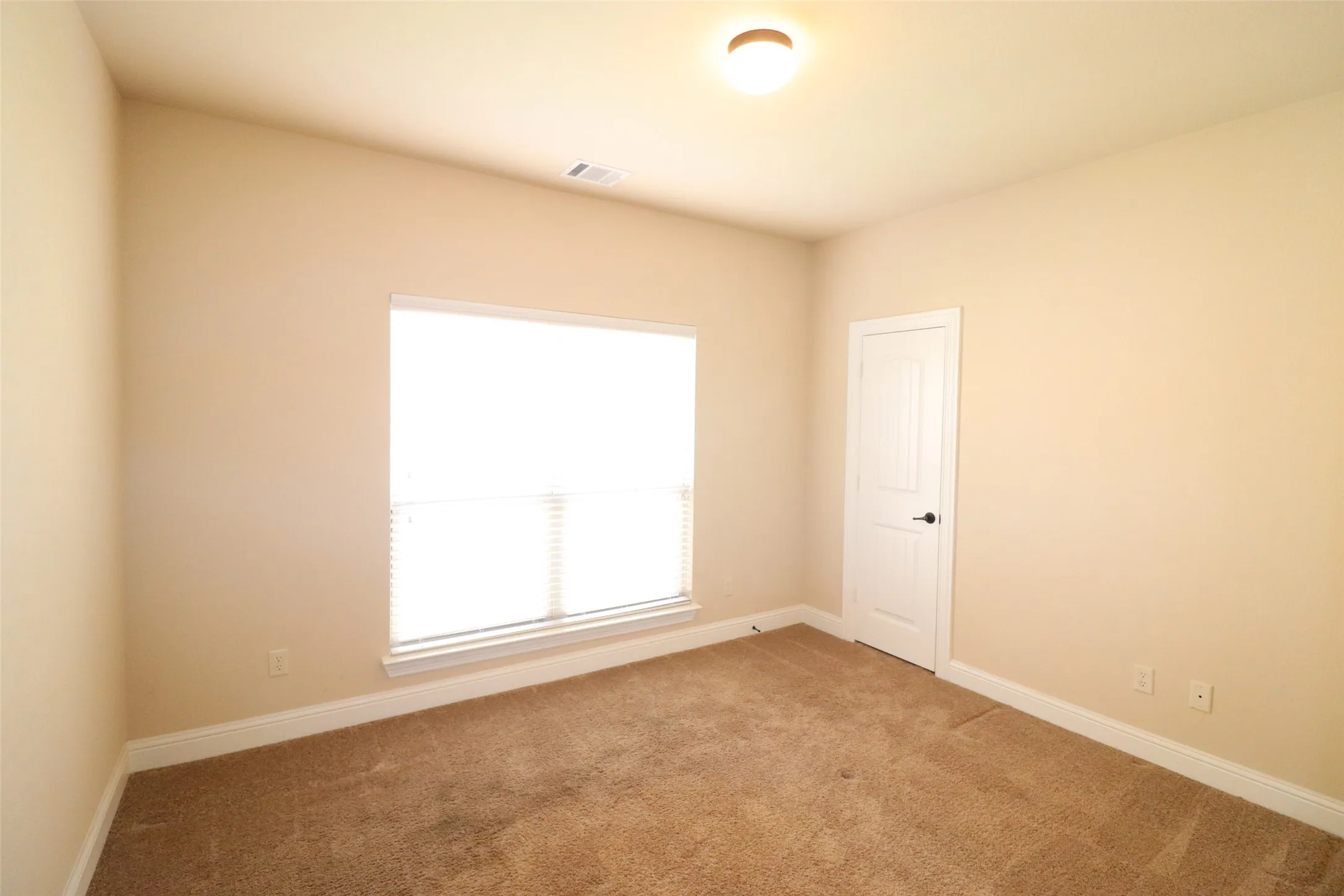 Vaulted ceiling, neutral wall tones, window with horizontal blinds, carpeted flooring, and a paneled interior door with matte black hardware