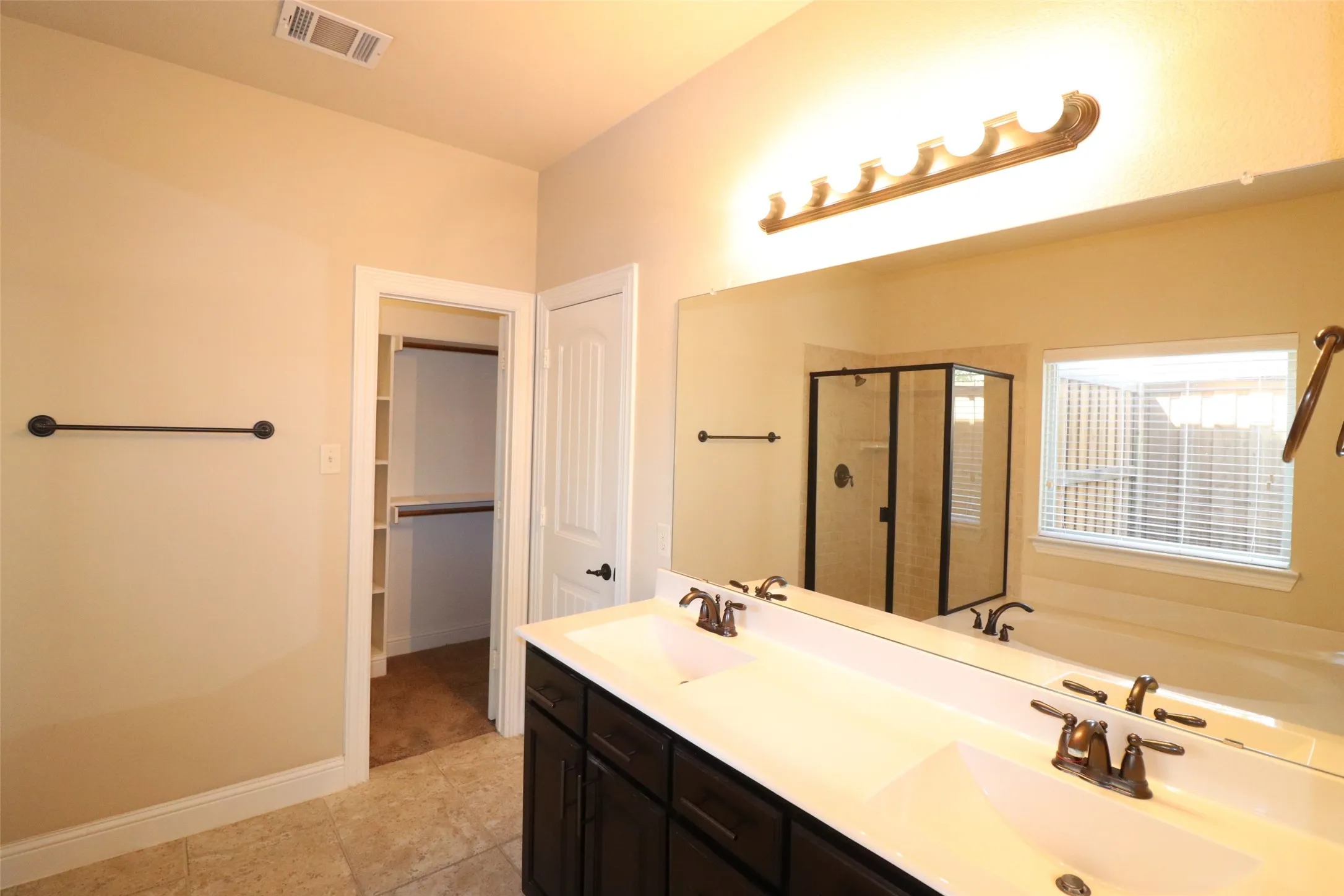 Dual vanity with bronze fixtures, full-width mirror, and built-in medicine cabinet