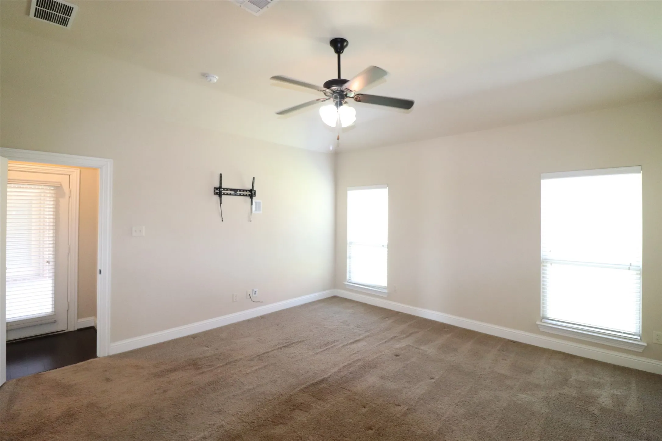 Carpeted flooring, two windows with blinds, ceiling fan, and painted walls