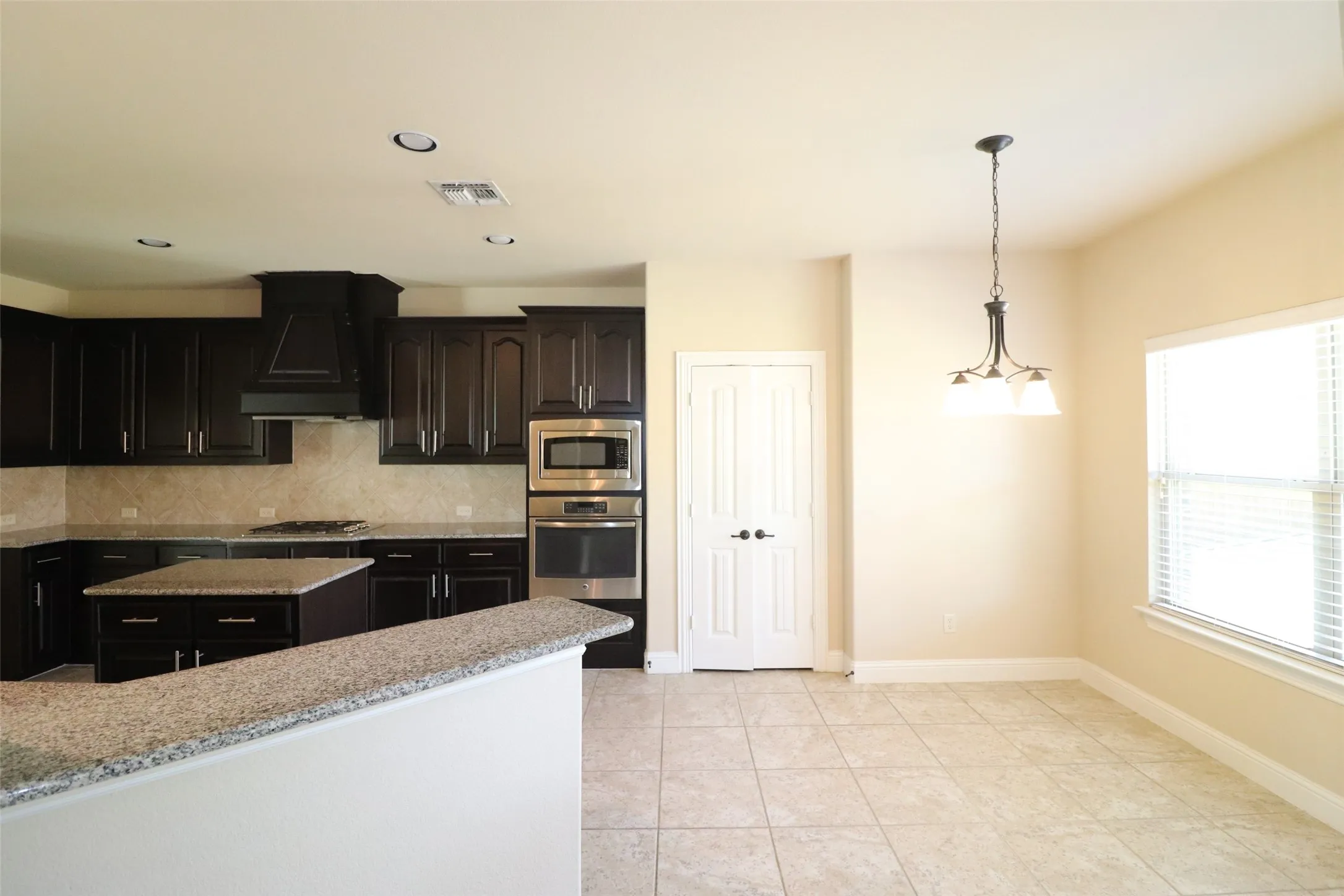 Kitchen featuring dark wood cabinetry, stainless steel appliances, a center island with countertop, and tile flooring