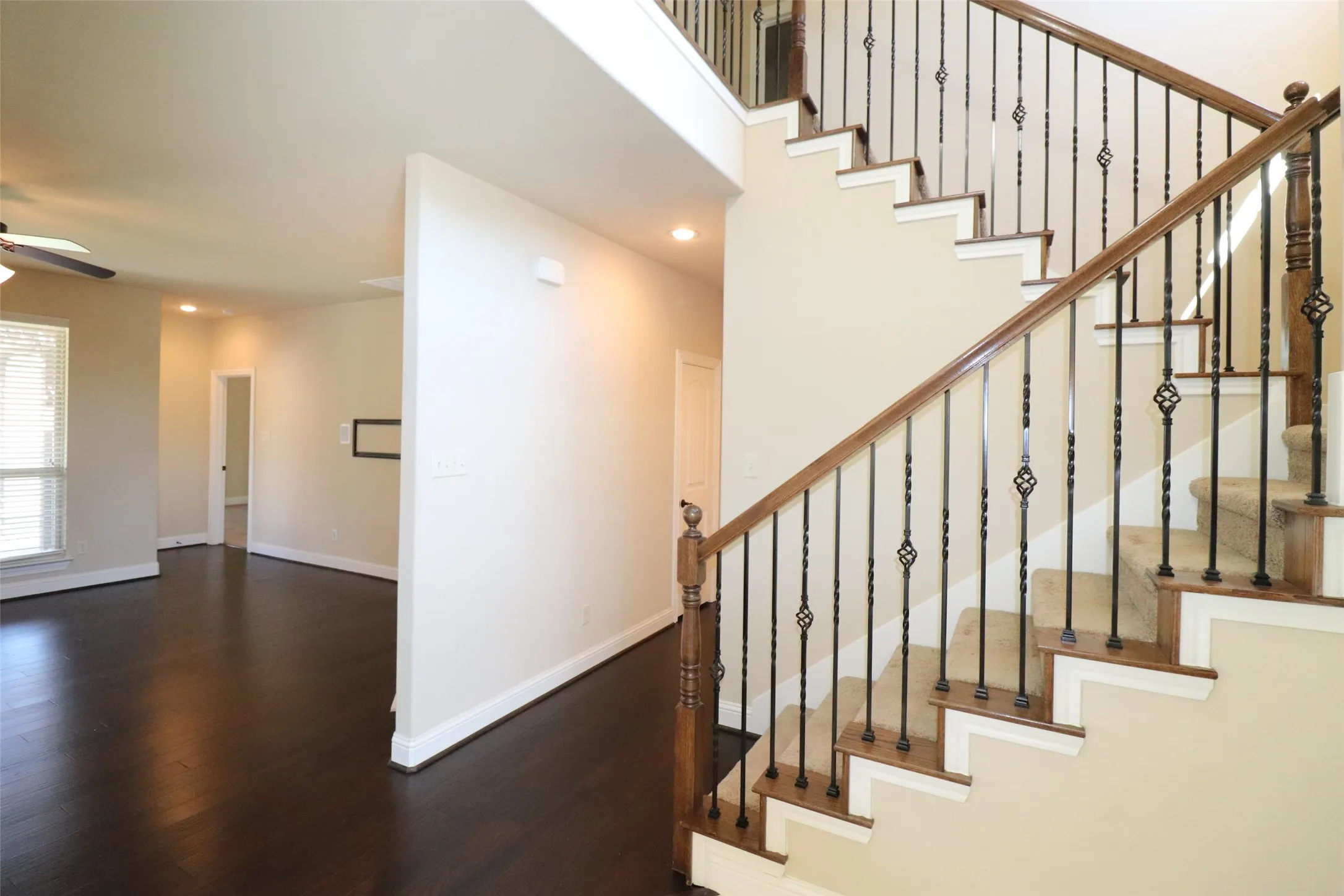 Two-story Foyer with a carpeted staircase, dark wood handrail, and wrought iron balusters