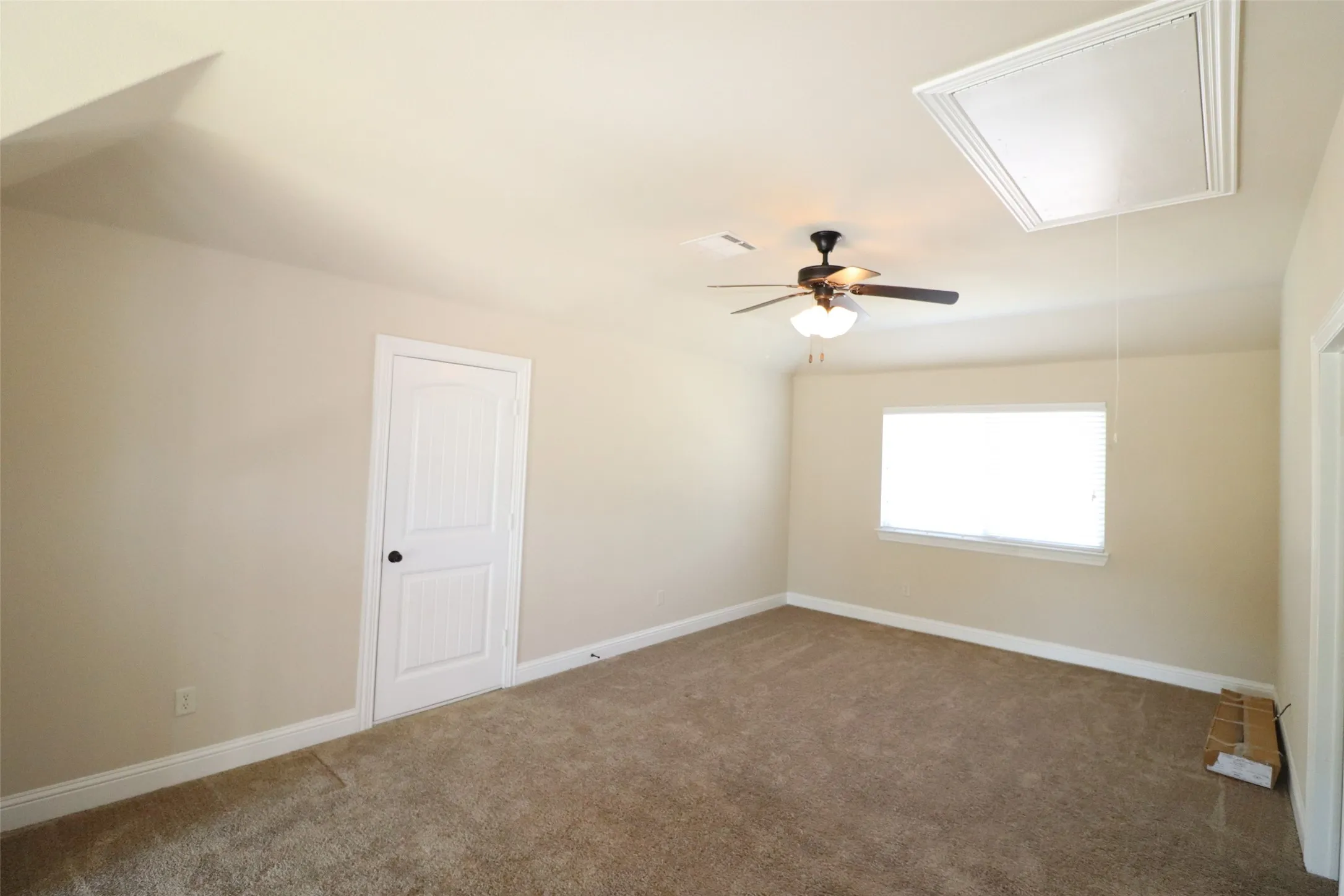 Carpeted room featuring a ceiling fan with light fixture, window with blinds, and white paneled door