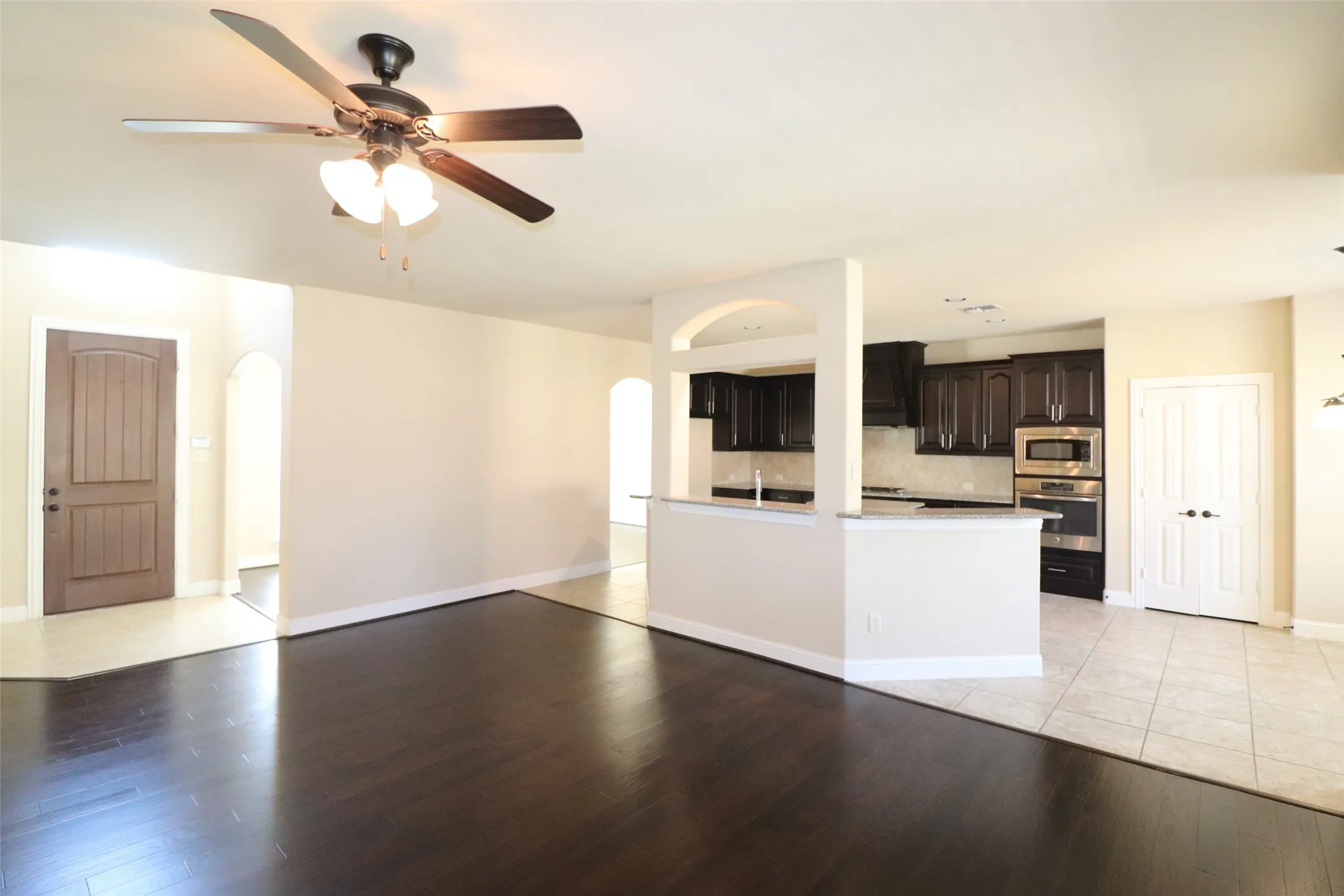Dark wood-finish flooring, recessed lighting, ceiling fan, dark wood cabinetry, and stainless steel built-in appliances