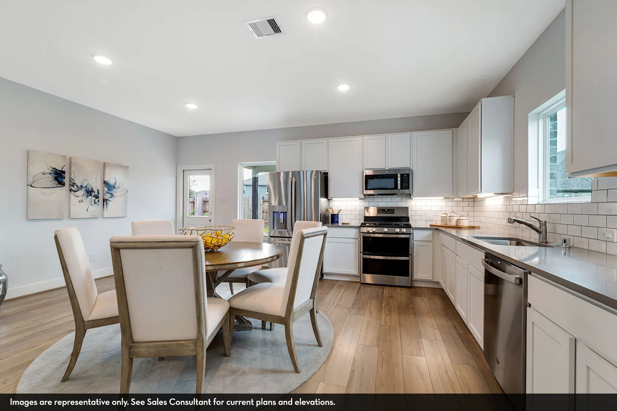 Open-concept kitchen and dining area featuring wood-finish flooring, white cabinetry, stainless steel appliances, subway tile backsplash, and recessed lighting