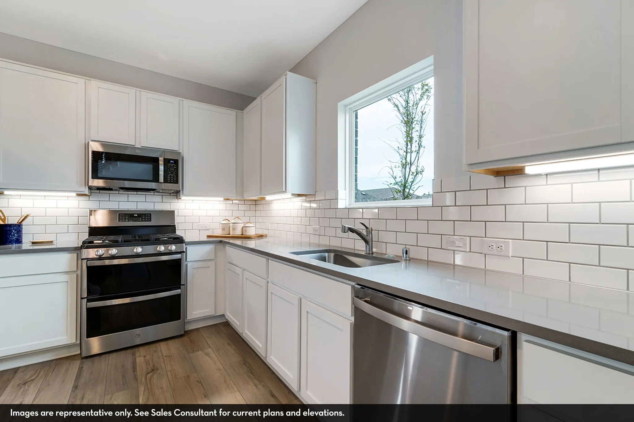 Kitchen featuring wood-finish flooring, white cabinetry, a white subway tile backsplash, stainless steel appliances, and a stainless steel sink with a single-handle faucet