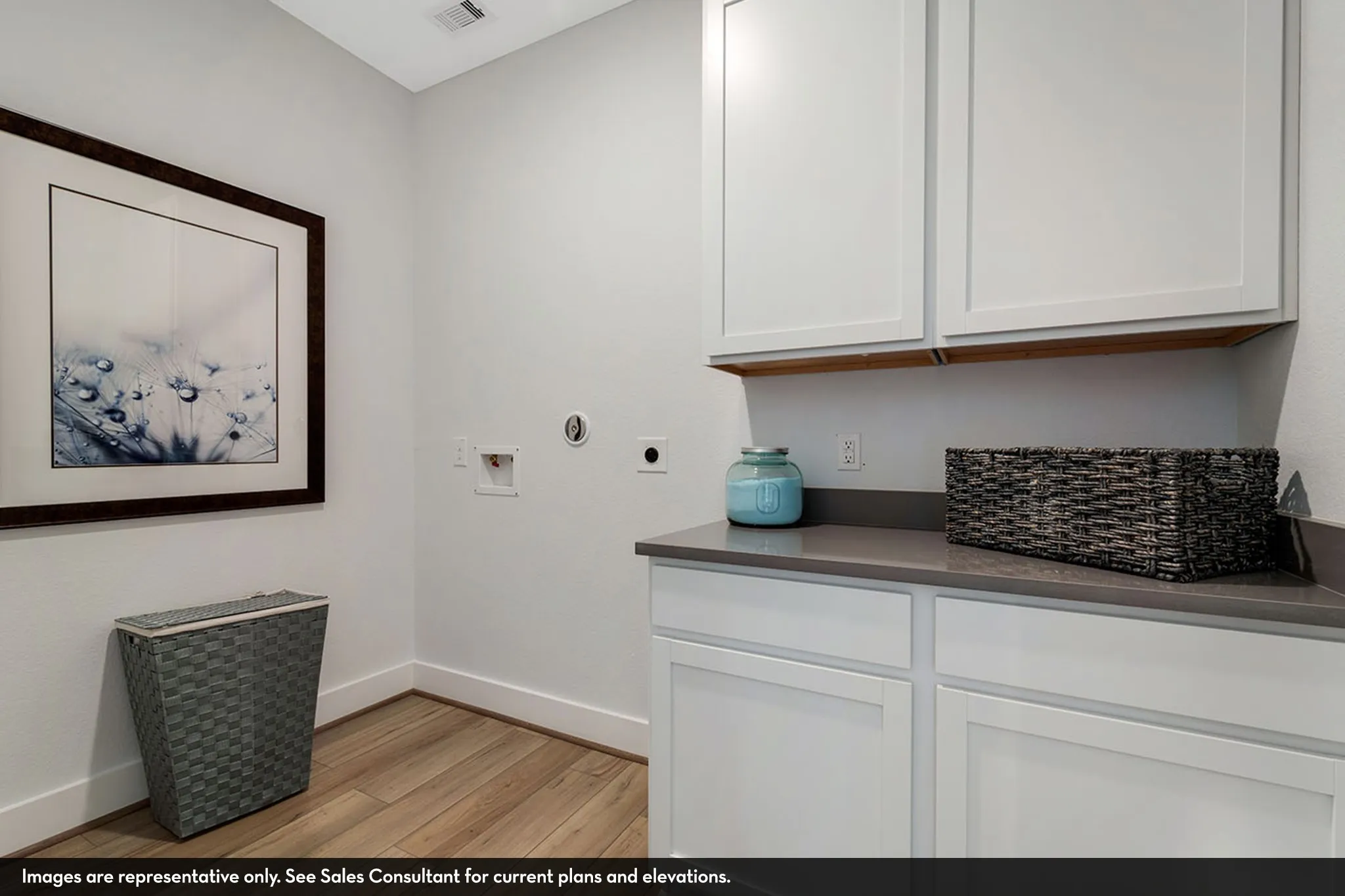 Laundry area featuring wood-finish flooring, white cabinetry, a built-in countertop, and an upper shelf