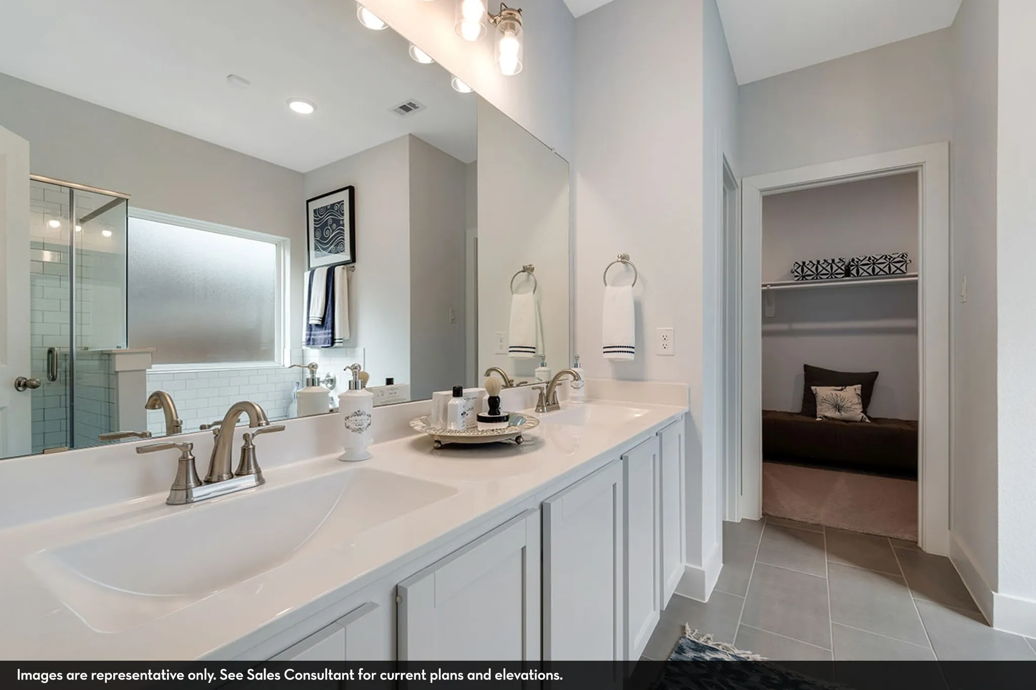 Double vanity with undermount sinks and brushed nickel fixtures, white cabinetry, a large frameless mirror, and a walk-in shower with subway tile surround