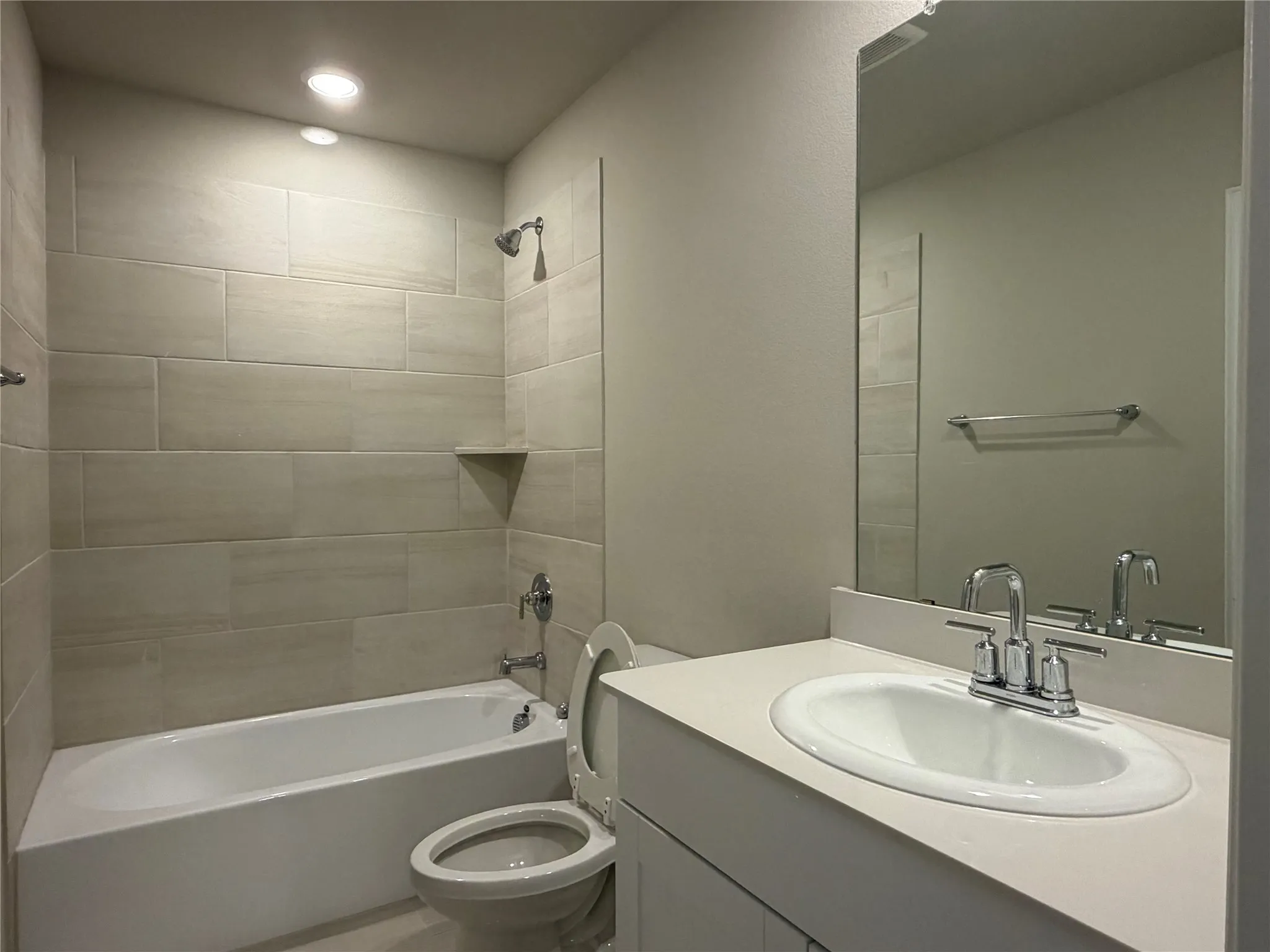 Integrated bathtub with tile surround, built-in shower niche, and recessed lighting