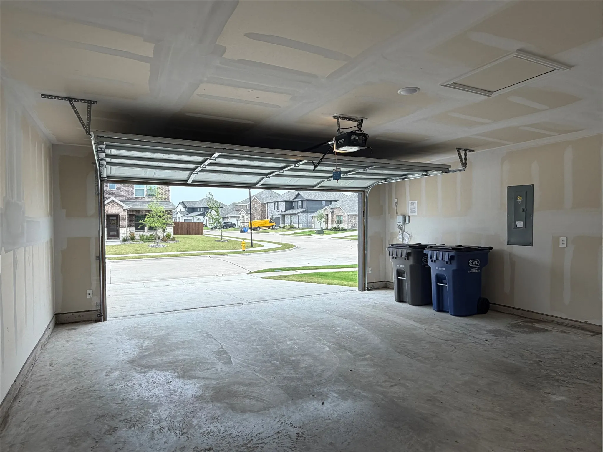 Attached garage with concrete flooring, overhead garage door system, and ceiling-mounted light fixture