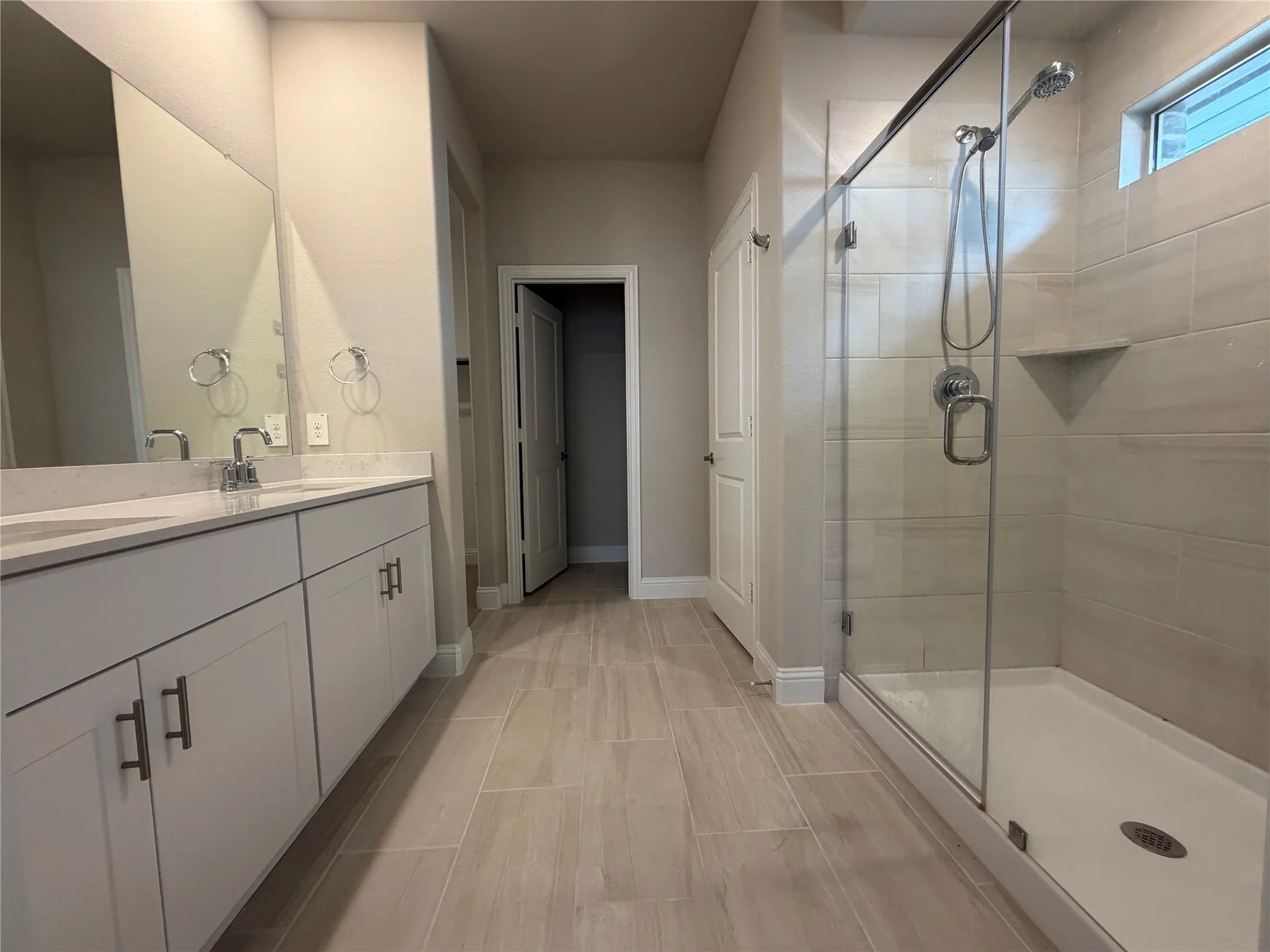 Dual vanity with rectangular sinks, a glass-enclosed shower, and wood-finish tile flooring