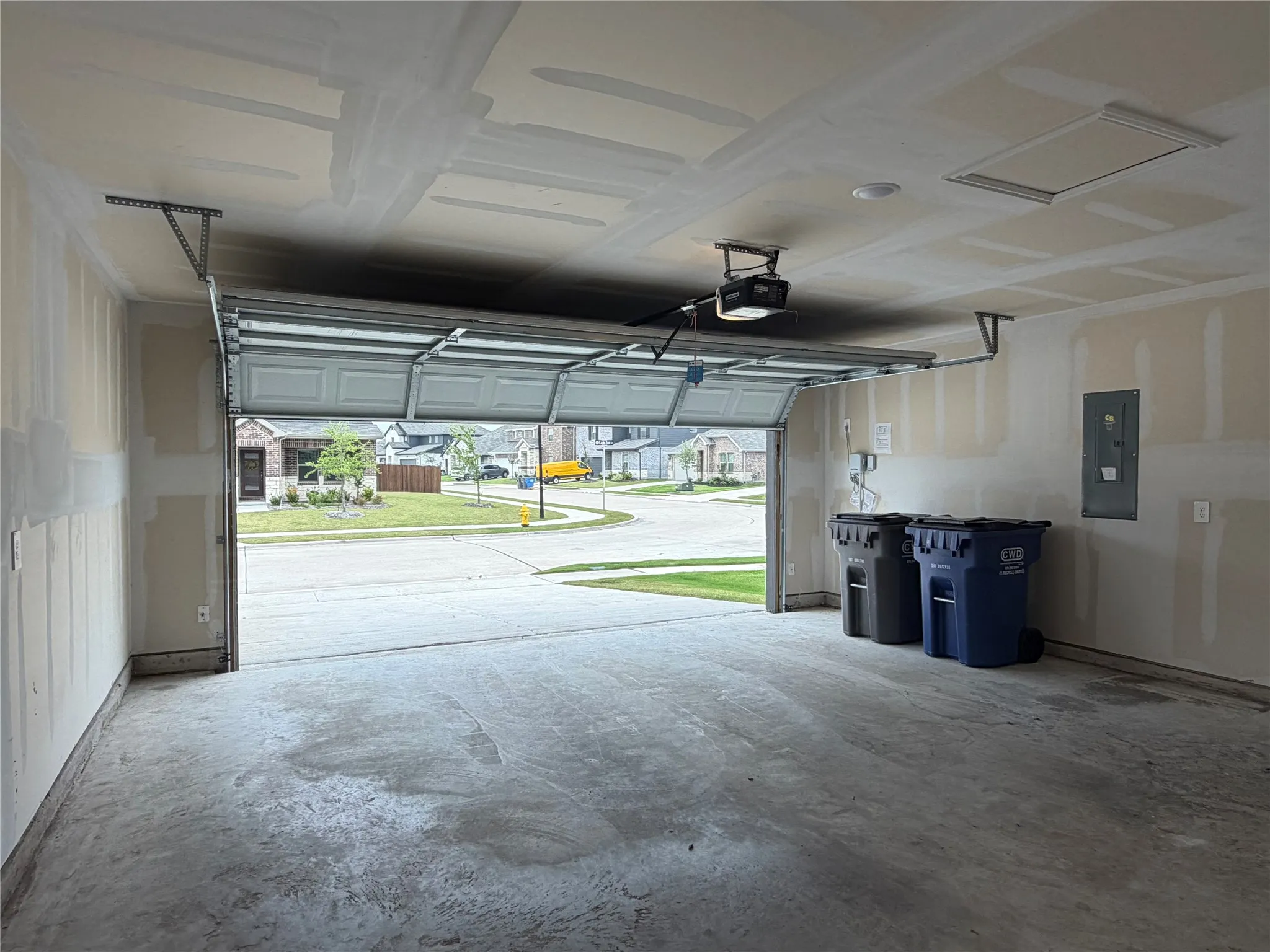 Concrete flooring garage with an automatic garage door opener, recessed lighting, and an access panel