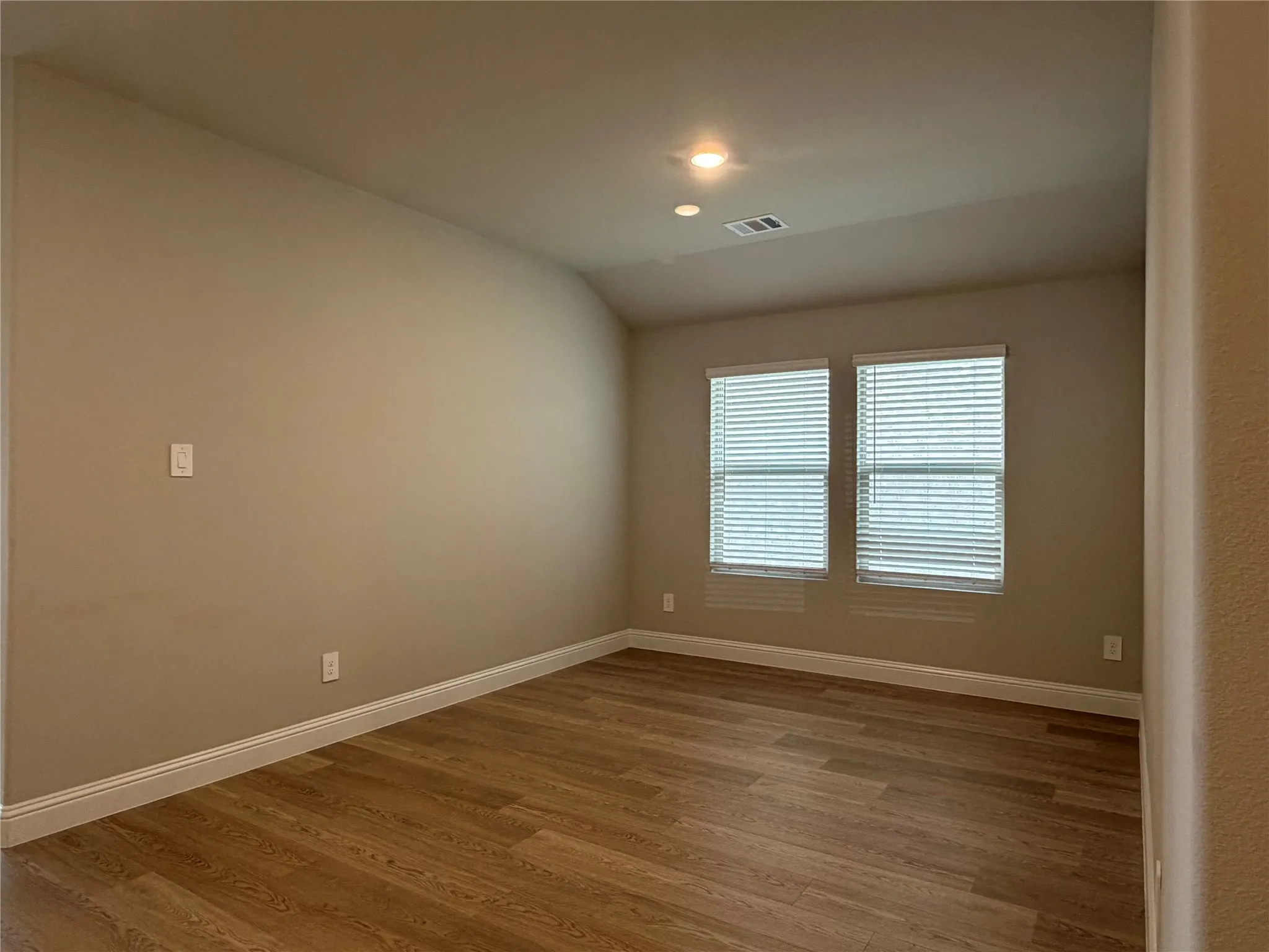Wood-finish flooring, recessed lighting, and dual windows with blinds