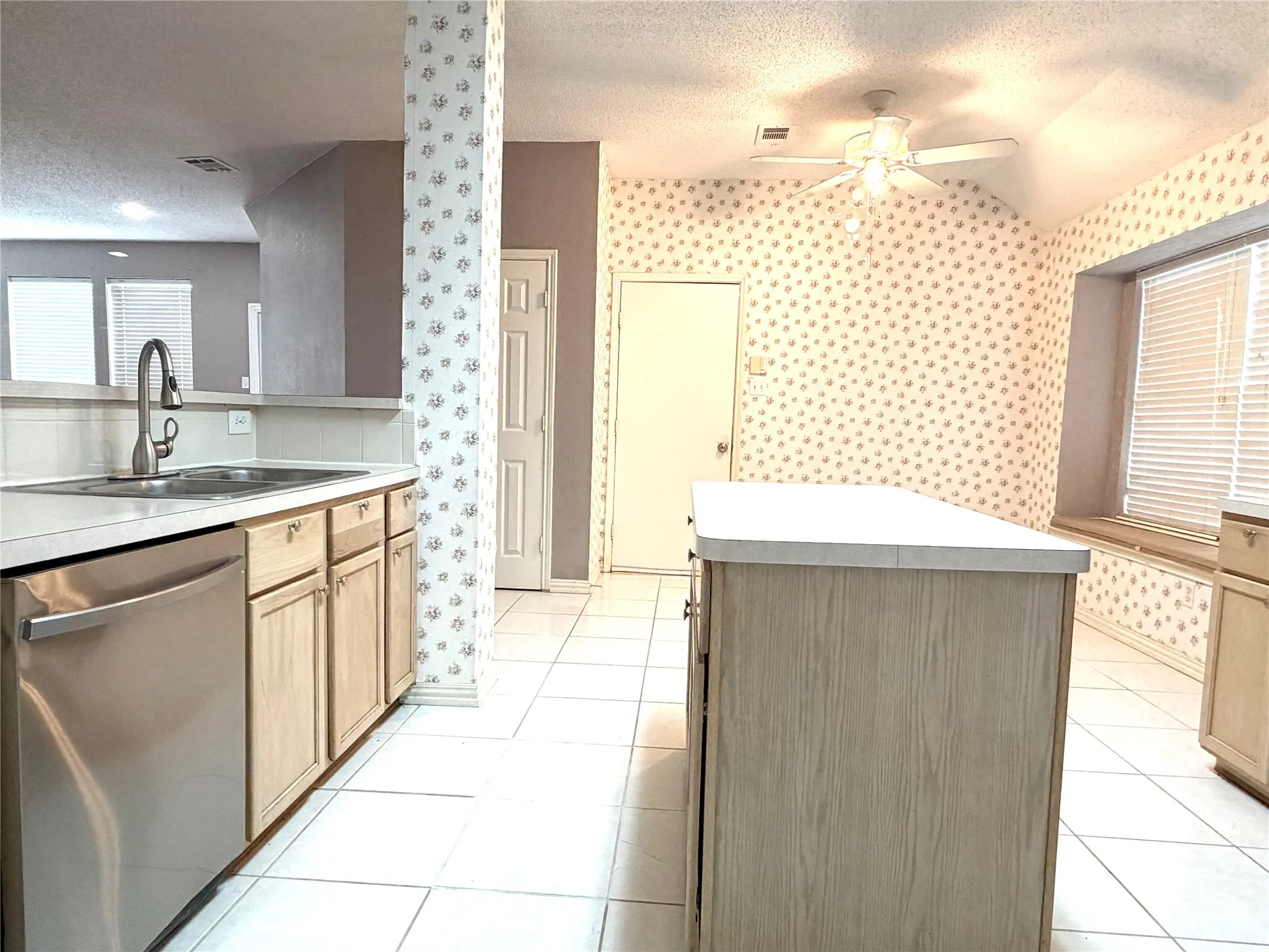 Kitchen featuring a stainless steel dishwasher, a kitchen island, tile flooring, and a ceiling fan