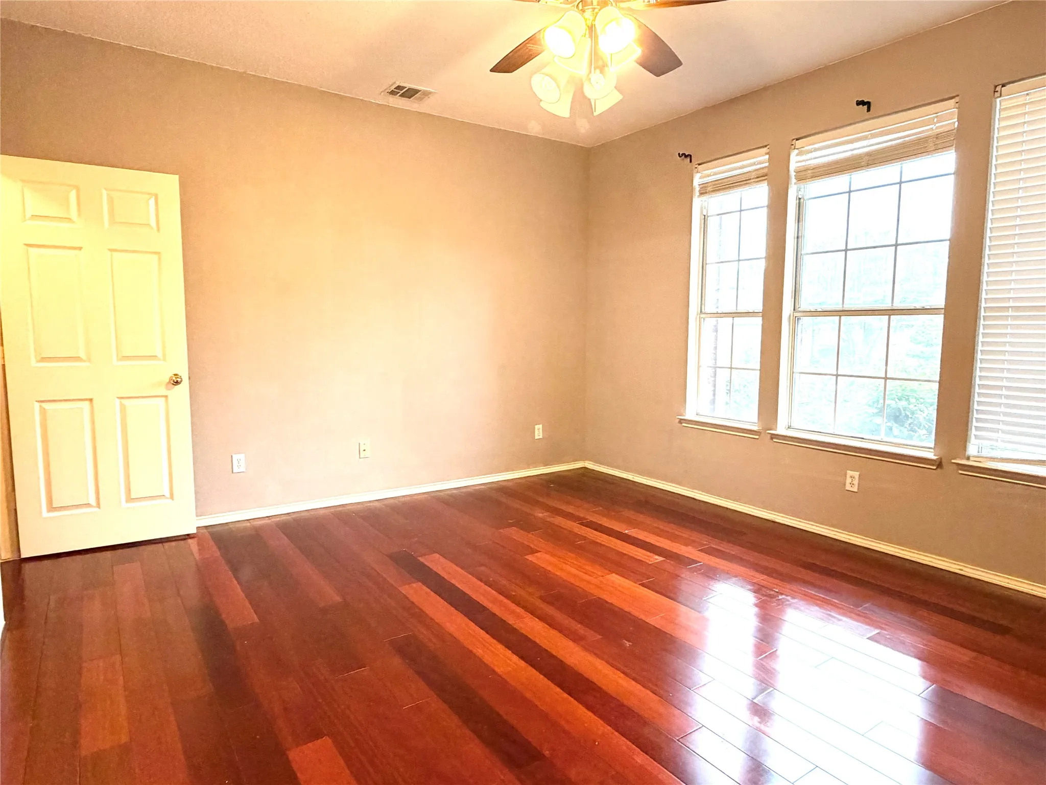 Rich wood-finish flooring with a ceiling fan light fixture