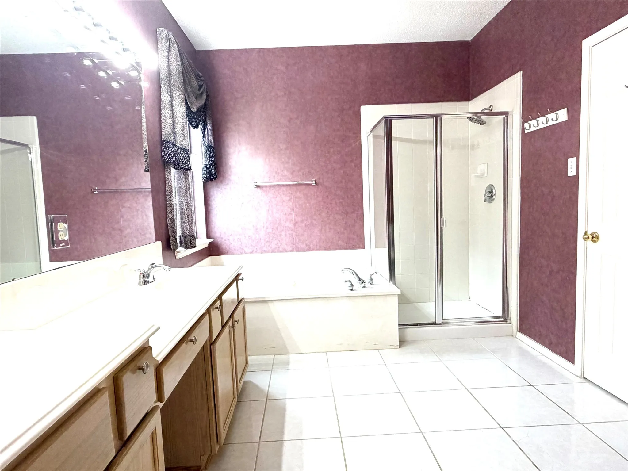 Dual vanity with integrated sinks, framed glass shower enclosure, built-in soaking tub, and tile flooring