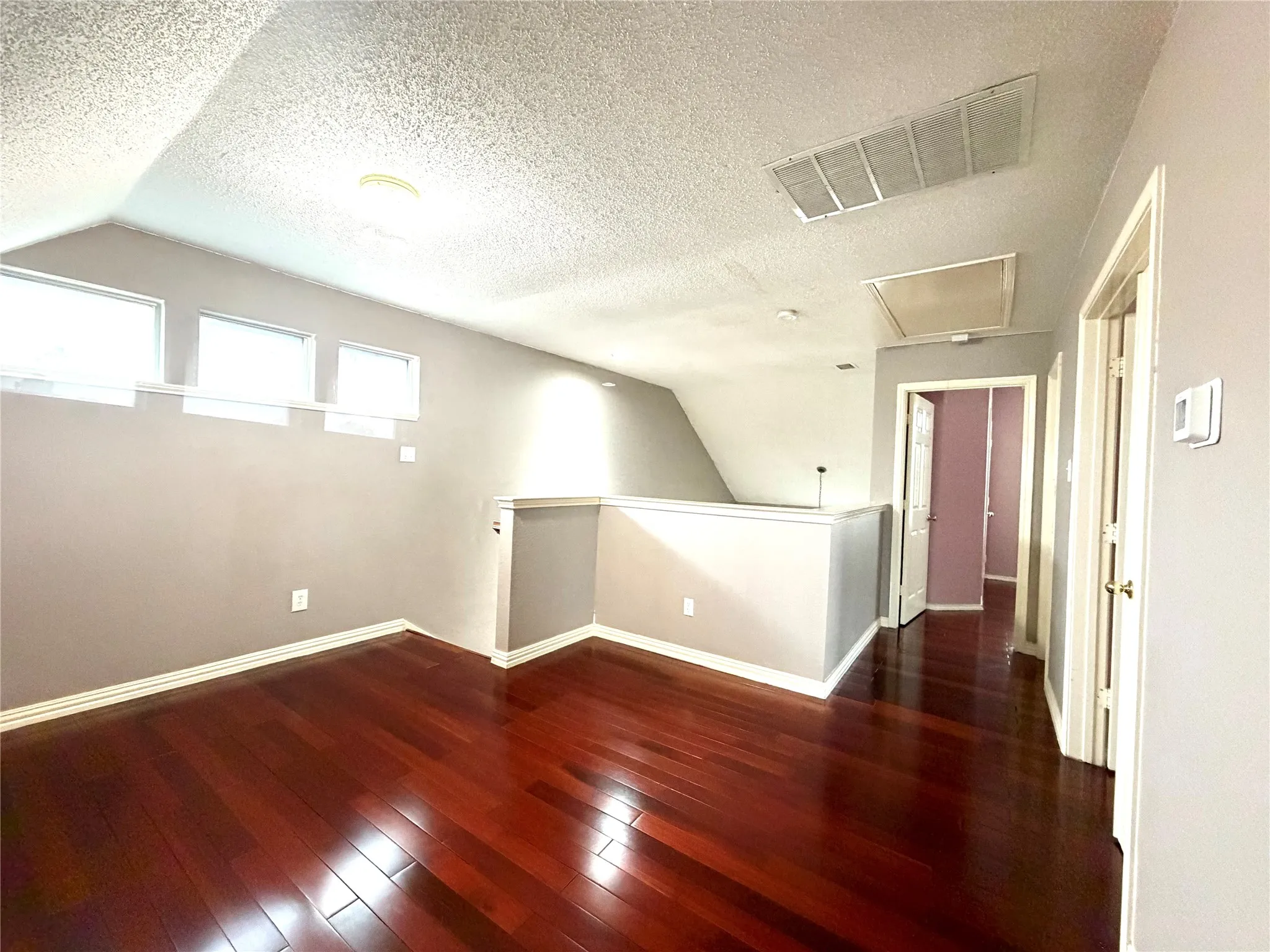 Hardwood-finish flooring, vaulted ceiling, and multiple windows