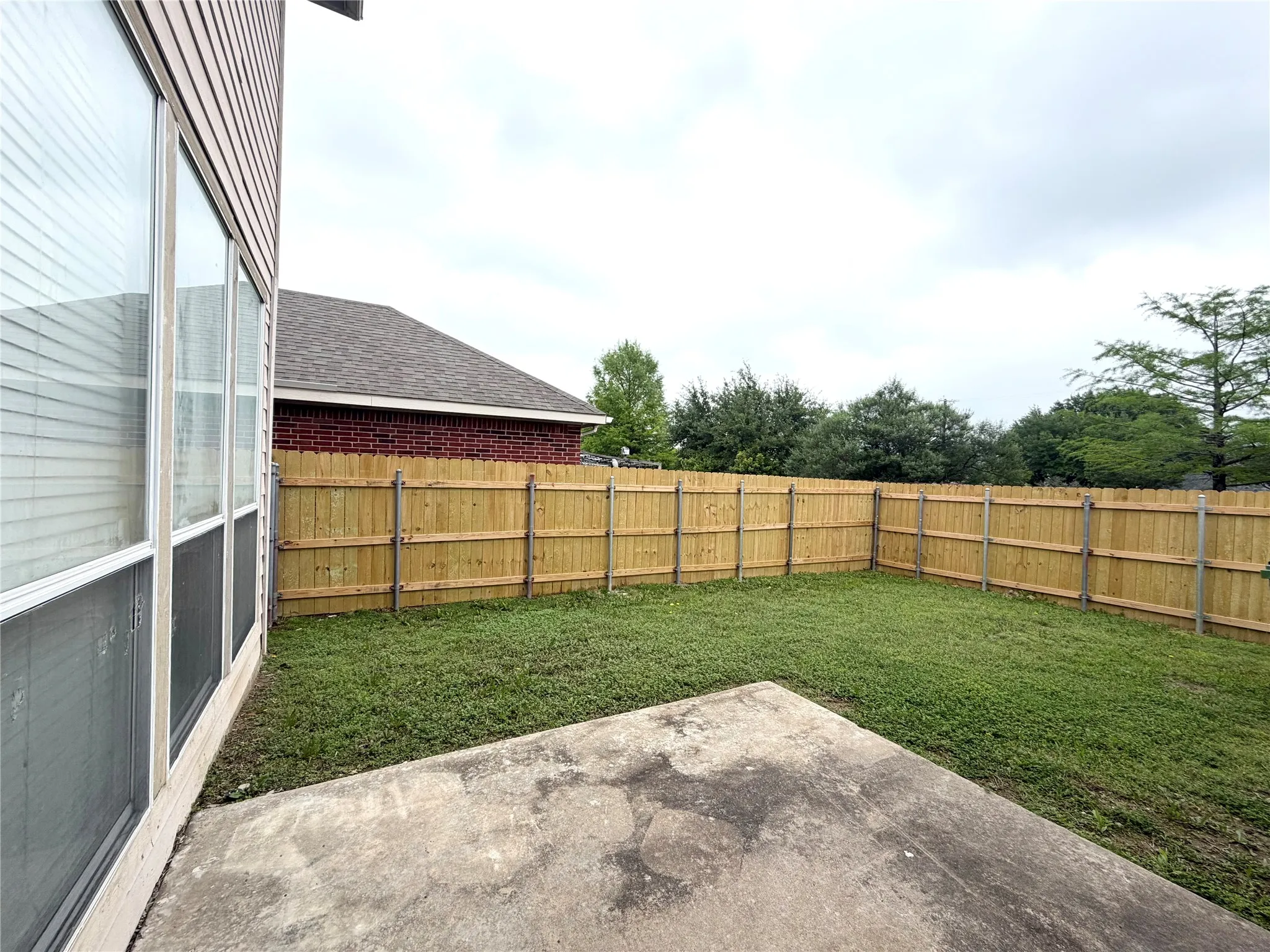 Private backyard featuring a wood privacy fence, concrete patio, and a manicured lawn