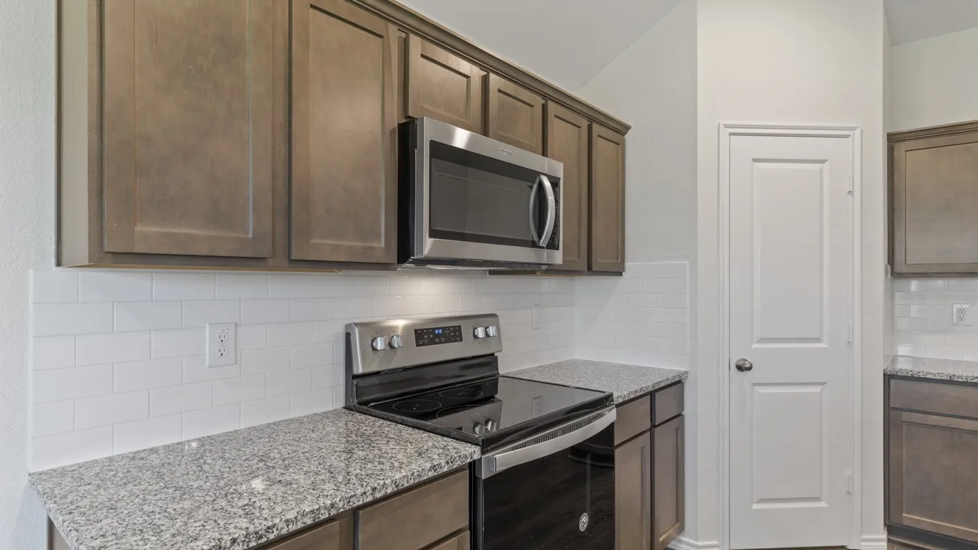 Stainless steel appliances, granite countertops, subway tile backsplash, and wood-finish cabinetry