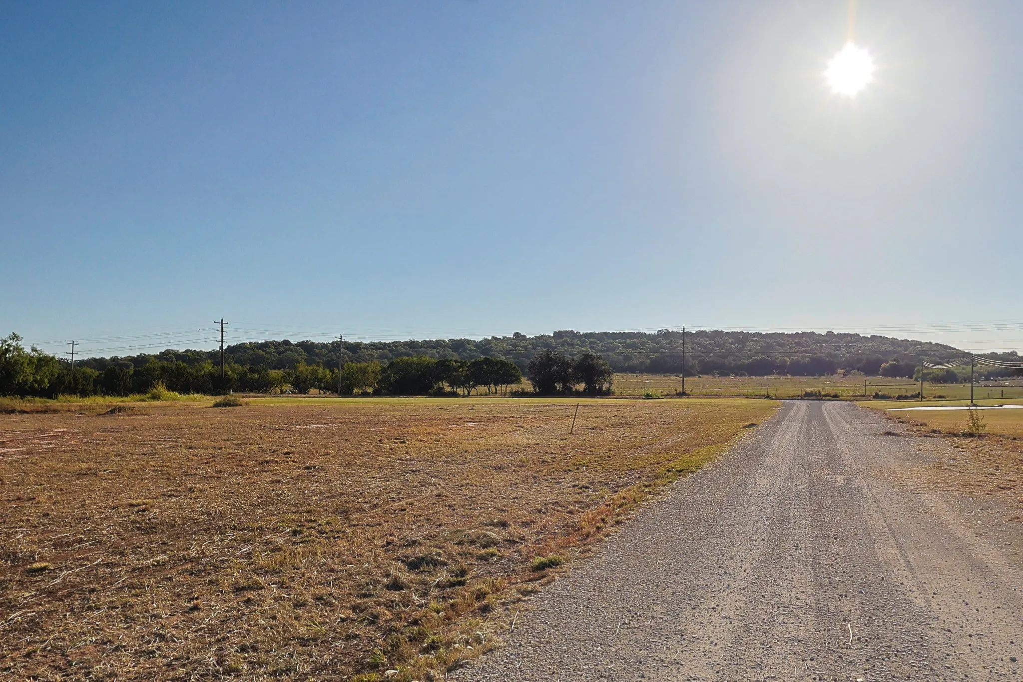 Expansive open land with a gravel road and distant tree line