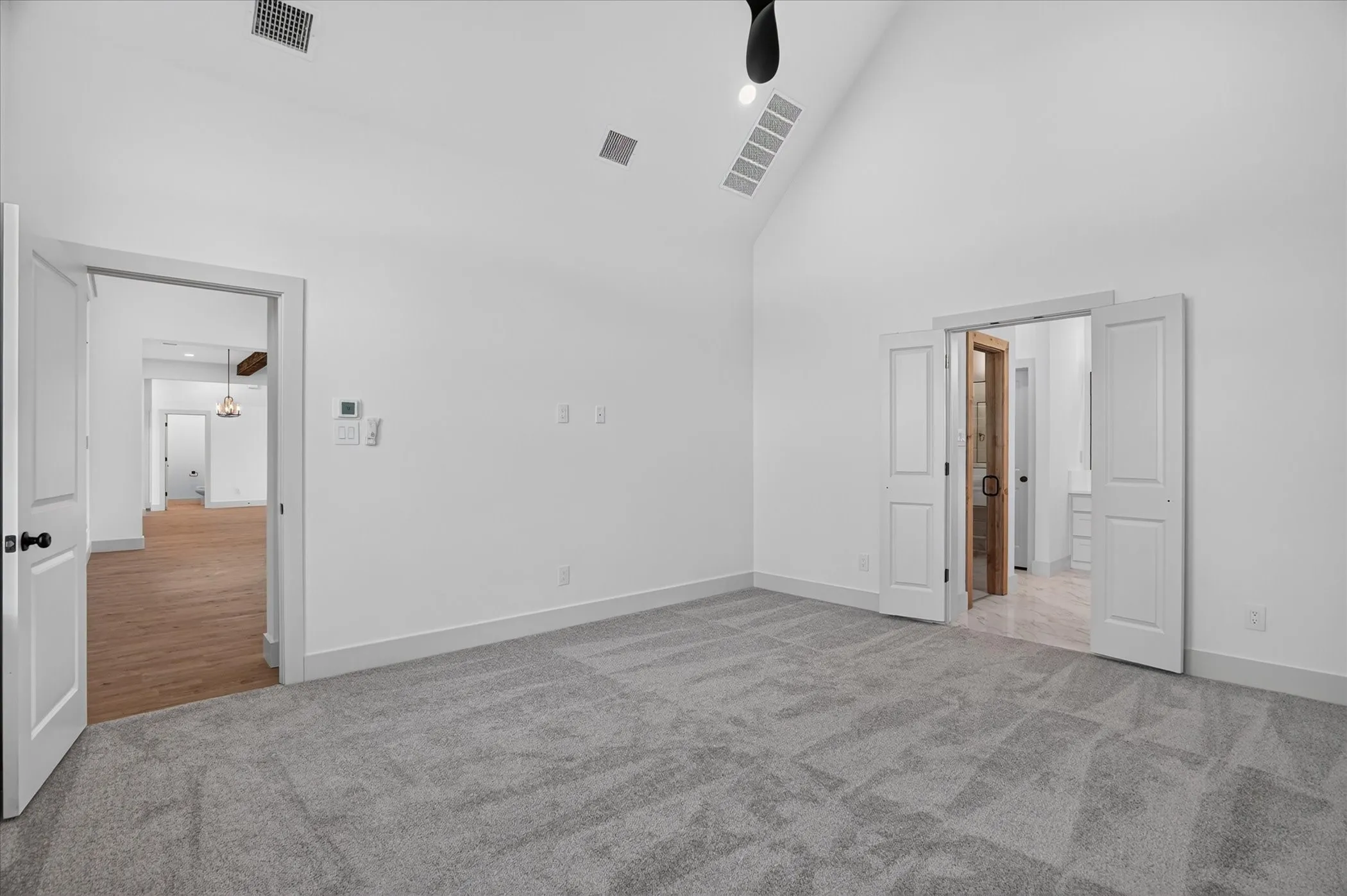 Vaulted ceiling with a ceiling fan, light gray carpeting, and white interior doors