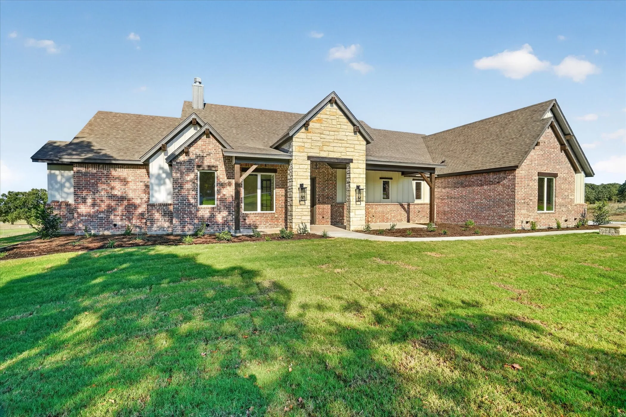 Exterior featuring a stone and brick facade, gabled rooflines, dark-framed windows, and an inviting covered entry