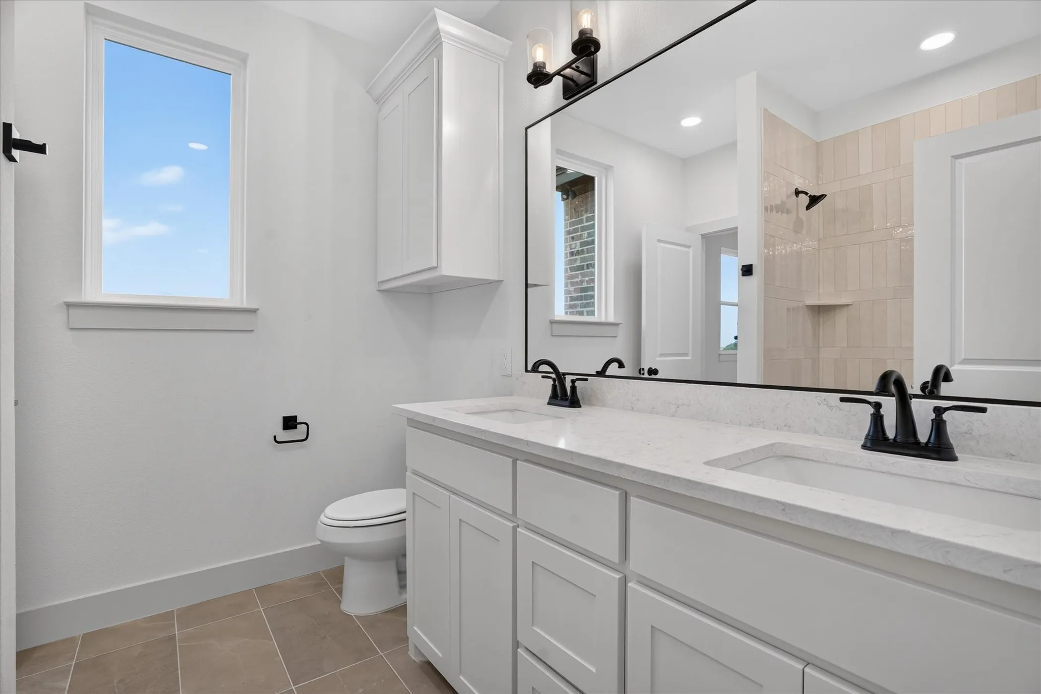 Dual vanity with white cabinetry and integrated sinks, quartz countertop, and matte black fixtures