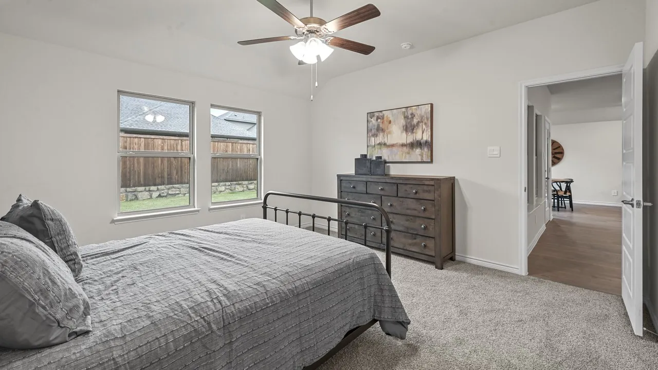 Carpeted bedroom with two windows, a ceiling fan with light, and a white interior door