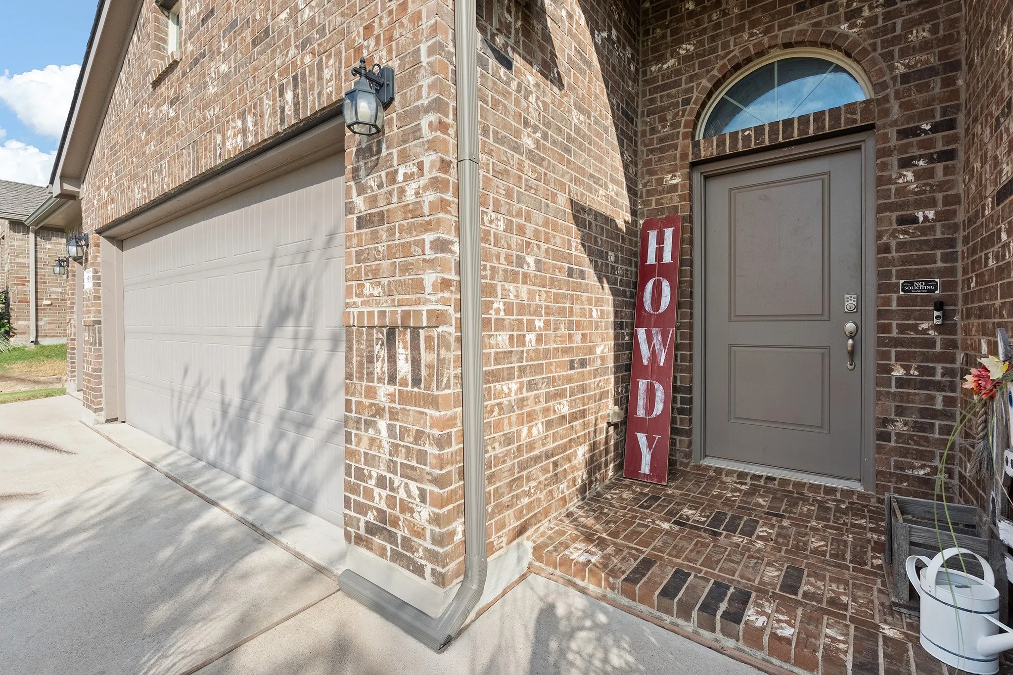 Brick exterior with an arched entryway, a panel-style front door, and an attached garage with a concrete driveway